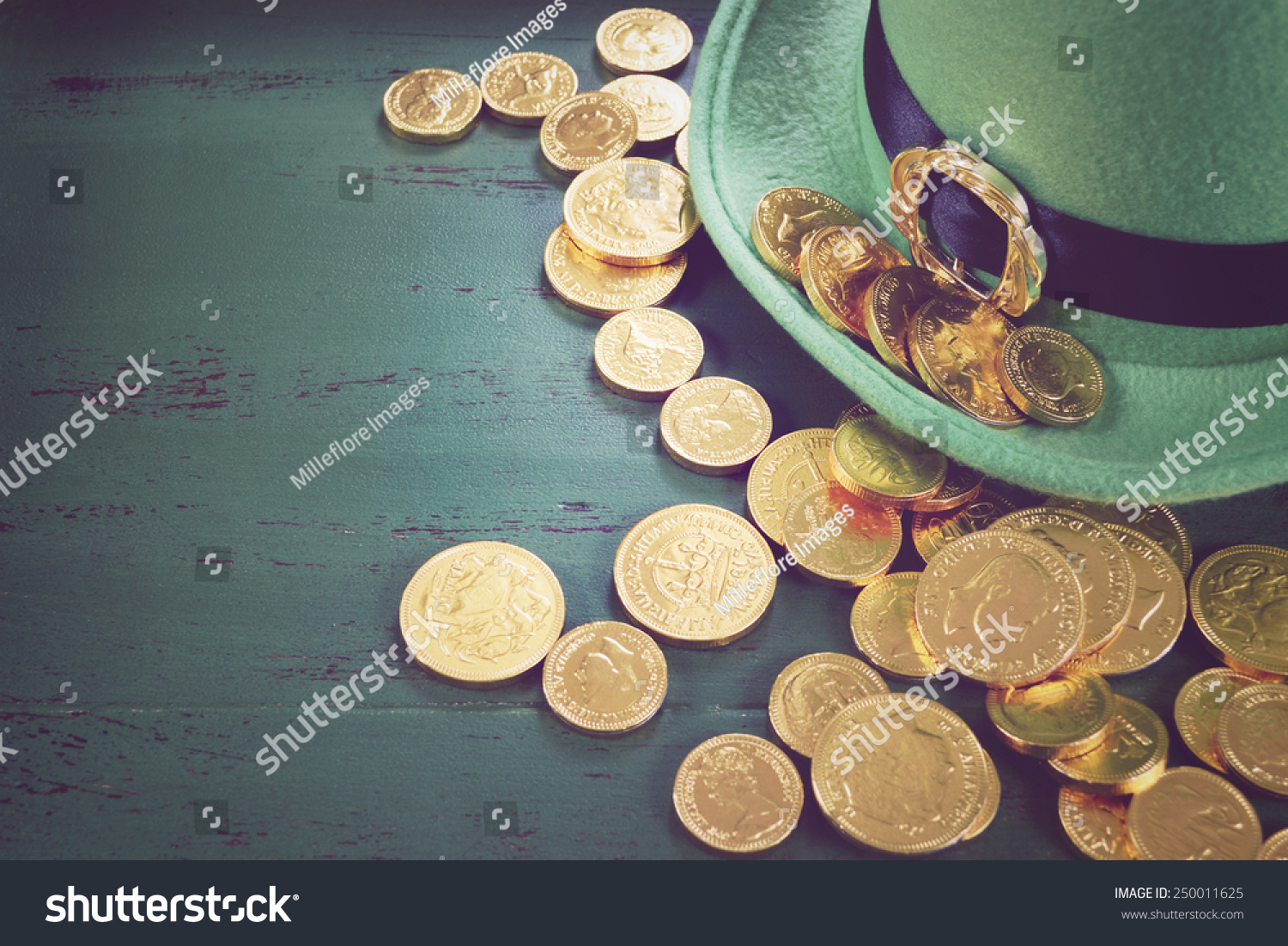 Happy St Patricks Day leprechaun hat with gold chocolate coins on vintage style green wood background, with retro vintage style filters. #250011625