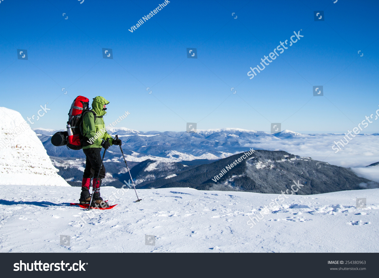 Winter hiking in the mountains on snowshoes with a backpack and tent. #254380963