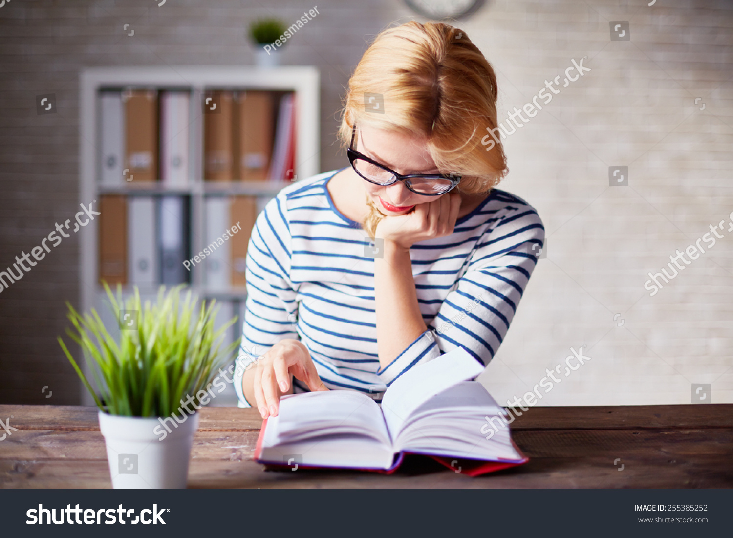 Charming girl sitting by wooden table and reading book #255385252