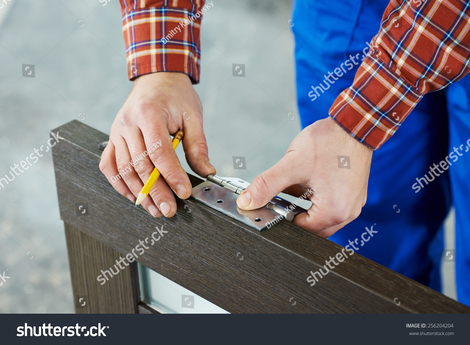 Close-up carpenter process of wood door hinge installation. #256204204