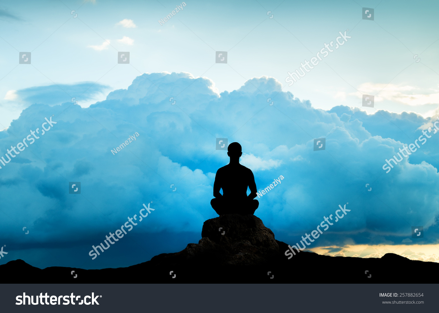 Silhouette of the meditating person against an approaching thunder-storm #257882654