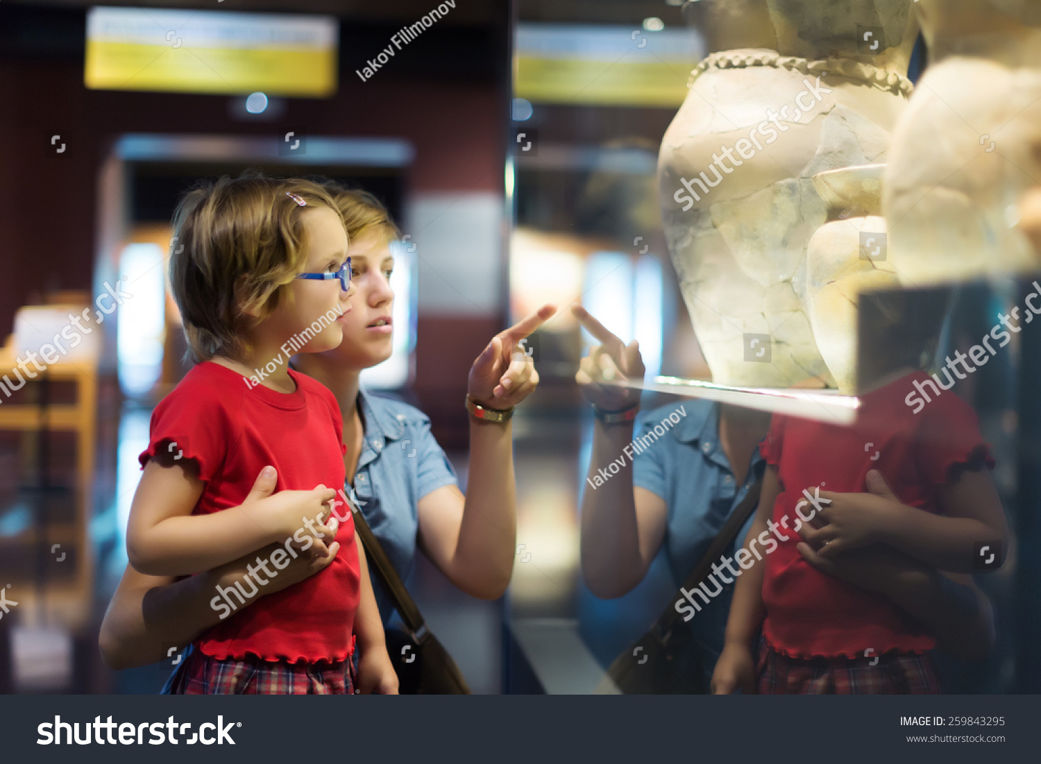 Woman and child looking old ancient amphora in historical museum #259843295