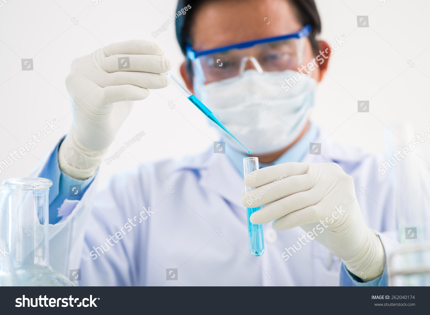 Scientist looking at tube with blue liquid #262040174