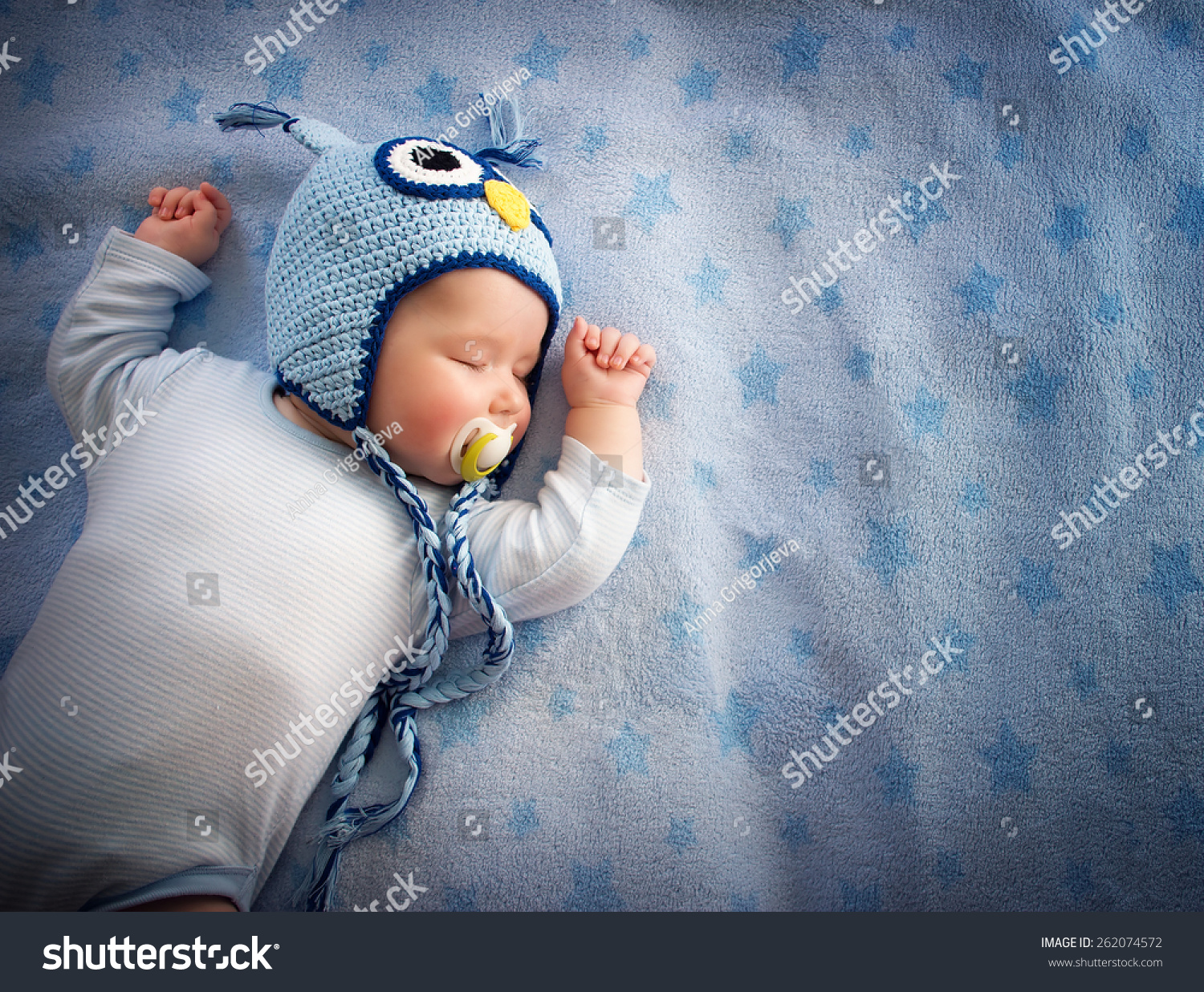 4 month old baby in owl hat sleeping on blue blanket #262074572