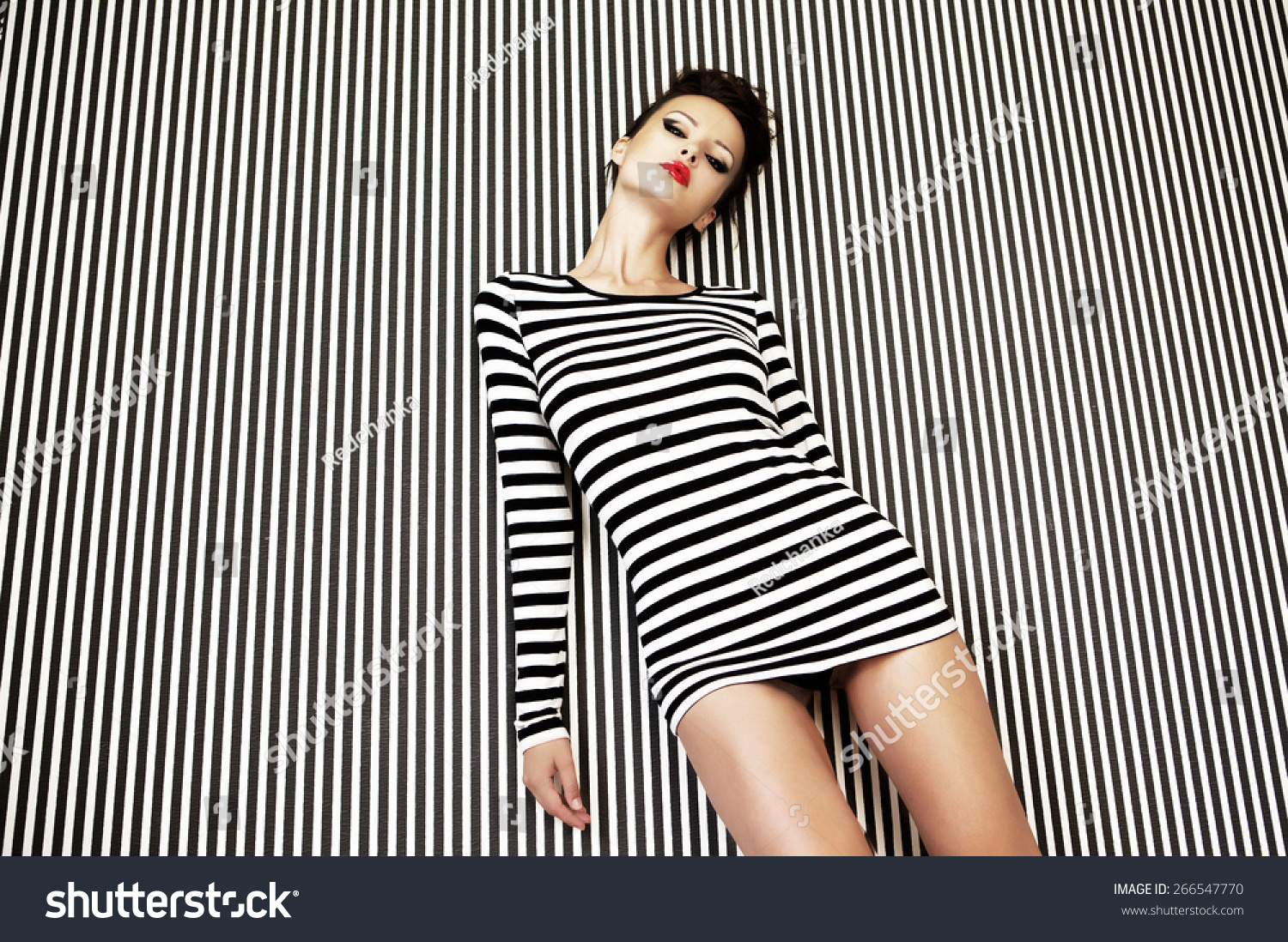 fashion woman in striped dress on striped background in studio #266547770
