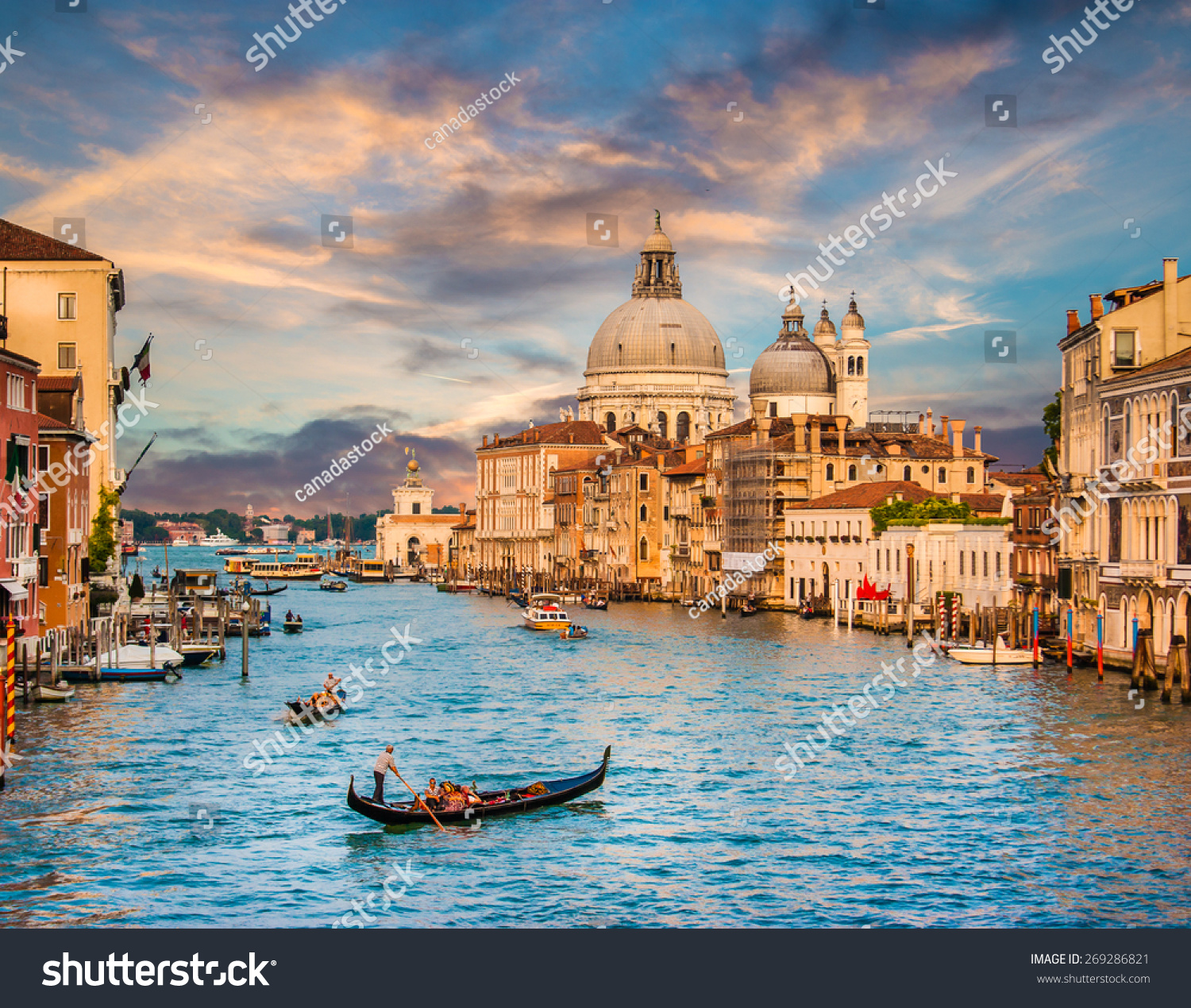Panoramic view of traditional Gondola on famous Canal Grande with Basilica di Santa Maria della Salute in beautiful golden evening light at sunset in Venice, Italy #269286821