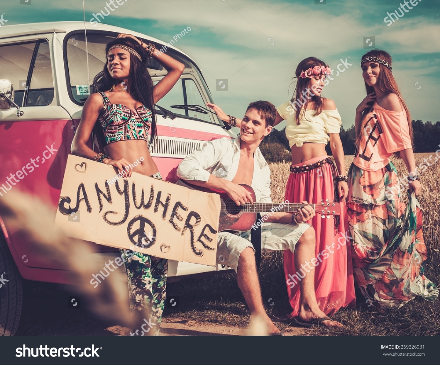 Multinational hippie hitchhikers with guitar and luggage on a road #269326931
