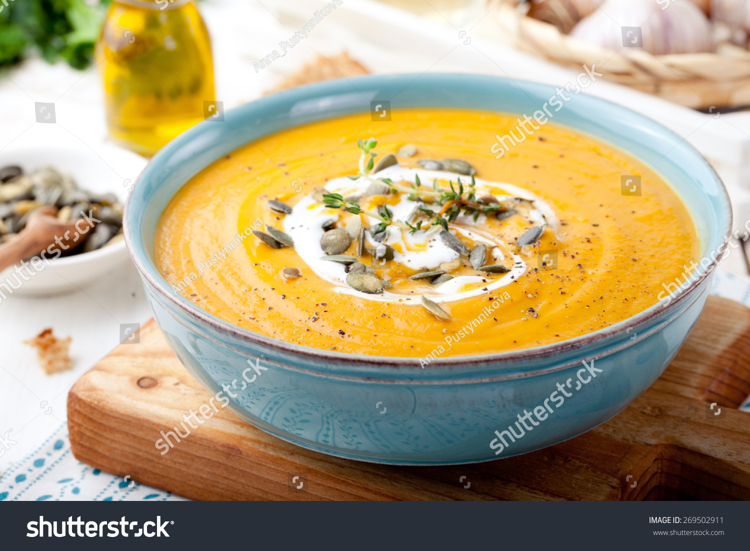 Roasted pumpkin and carrot soup with cream and pumpkin seeds on white wooden background. Copy space #269502911