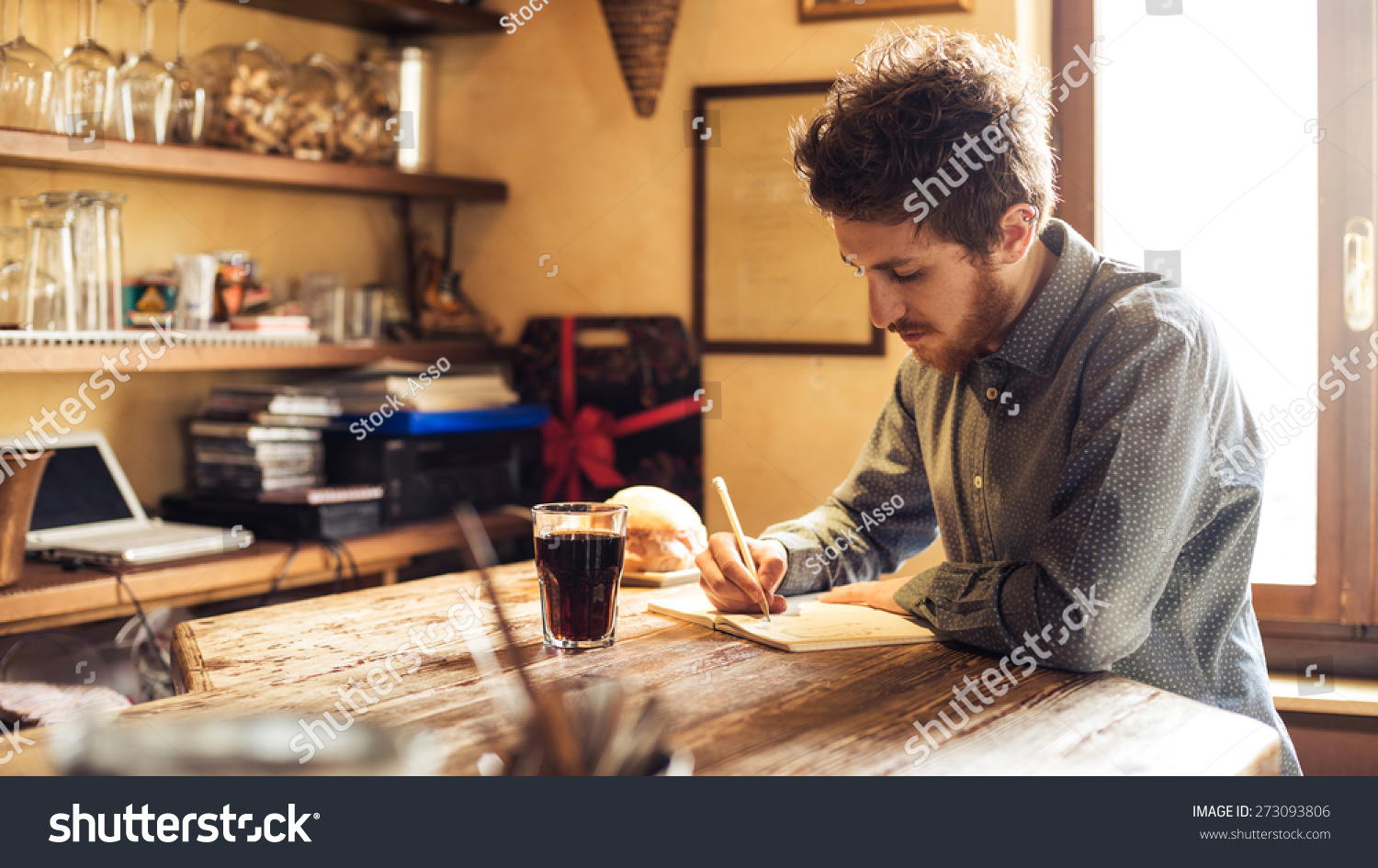 Young hipster man sketching on a notebook in his studio on a rustic wooden table #273093806