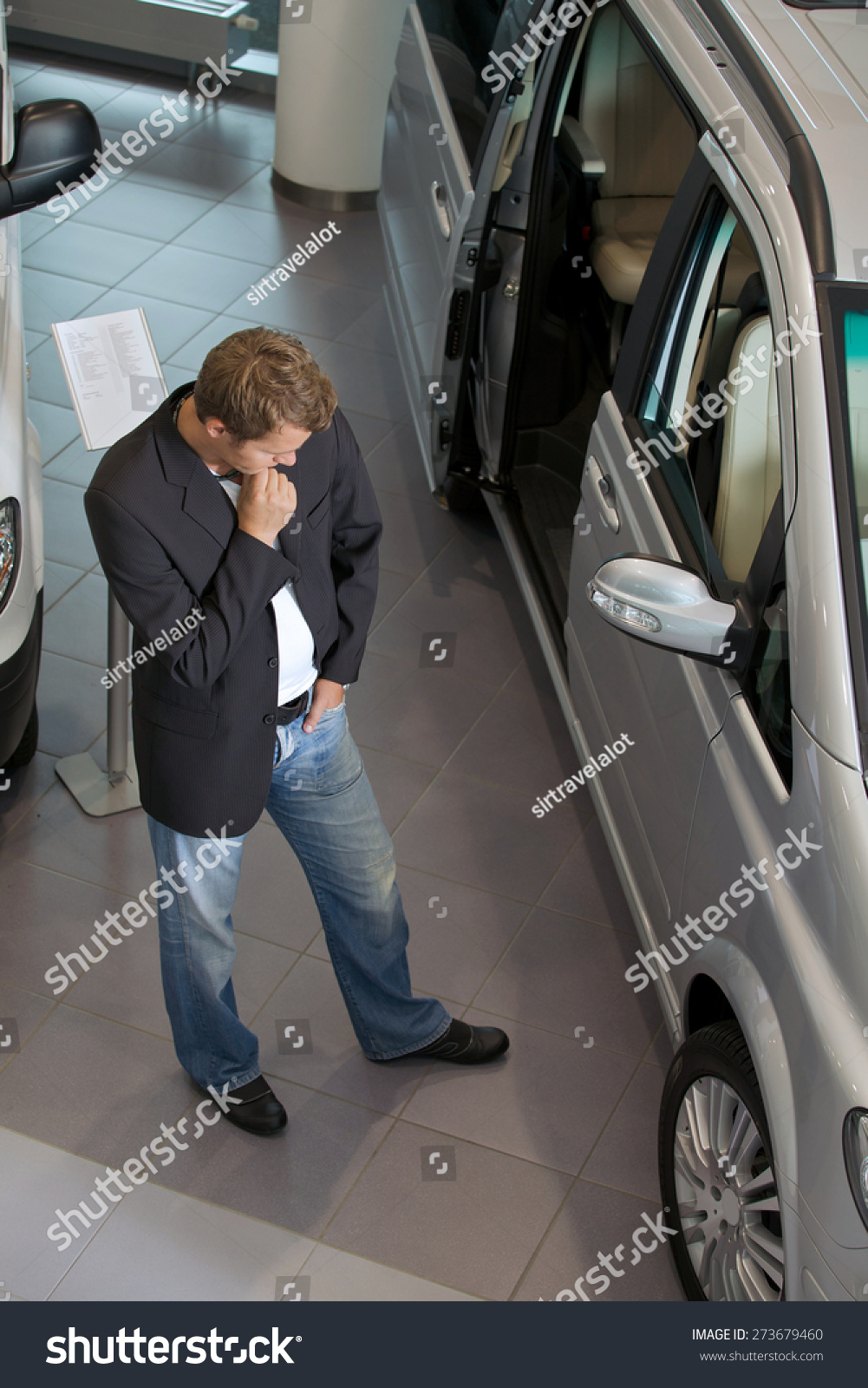 Young man examining new car at showroom #273679460