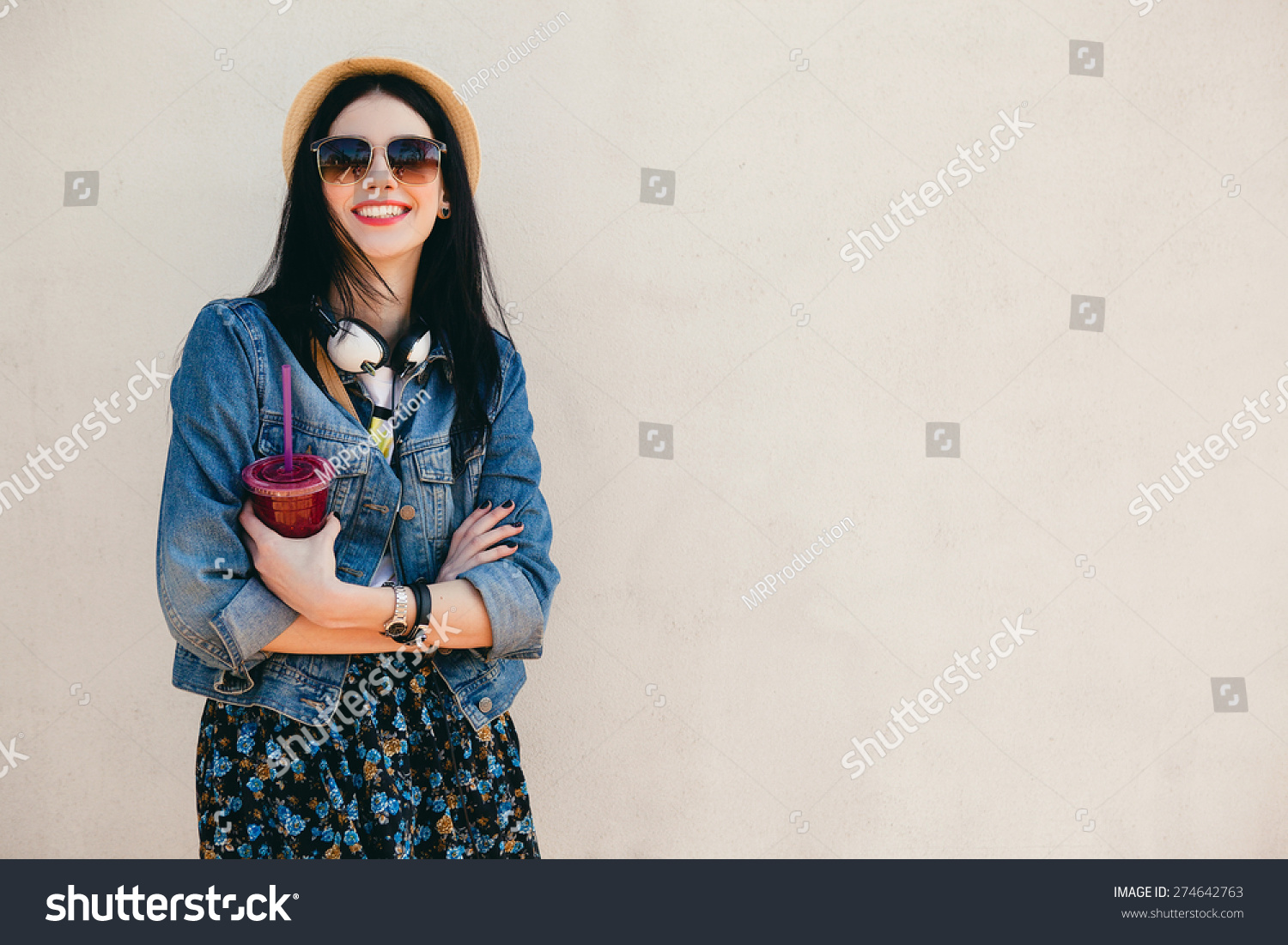 young beautiful happy stylish hipster girl, cocktail, smoozy drink, denim jacket, smiling, fashion, teen, cool accessories, purse, hat, sunglasses, amazed, vintage style, wall background, hair, wind #274642763