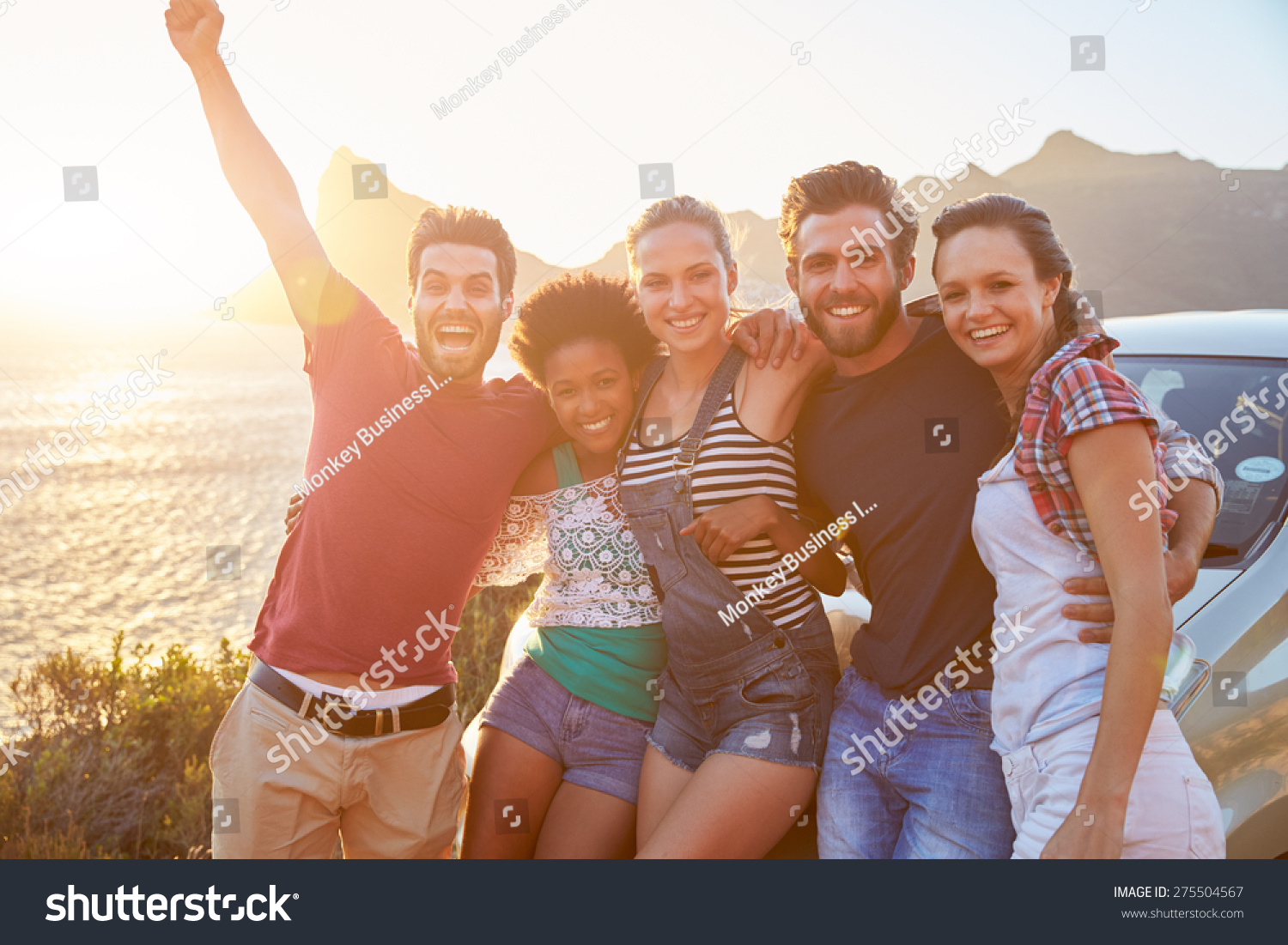 Group Of Friends Standing By Car On Coastal Road At Sunset #275504567