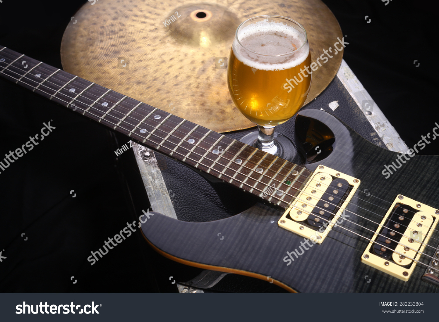 Glass full of light beer standing on a case with some music equipment #282233804