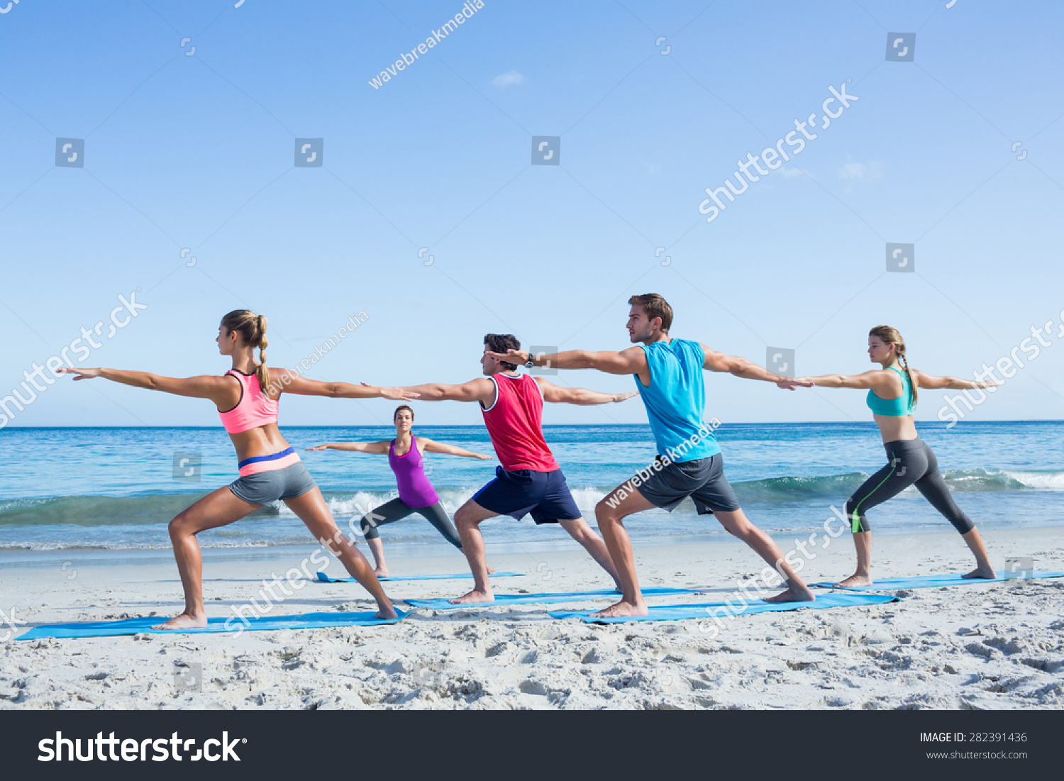 Friends doing yoga together with their teacher at the beach #282391436