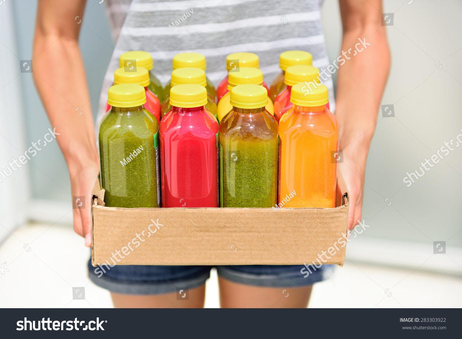 Juicing cold pressed vegetable juices for a detox diet. Dieting by cleansing your body from toxins with raw organic fruits and vegetables juice made fresh and delivered in bottles. #283303922