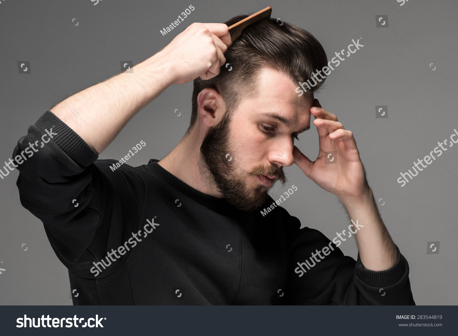 young man comb his hair on gray background #283544819