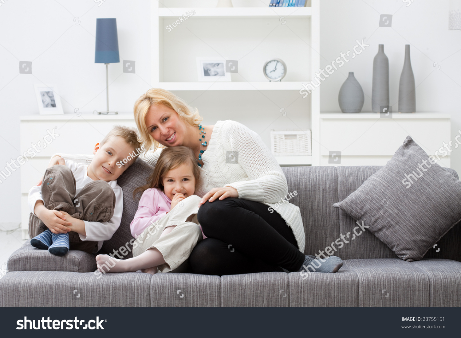 Mother and children sitting together on couch at living room. #28755151