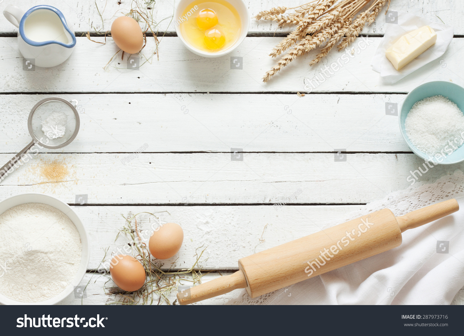 Baking cake in rustic kitchen - dough recipe ingredients (eggs, flour, milk, butter, sugar) on white planked wooden table from above. Background layout with free text space. #287973716