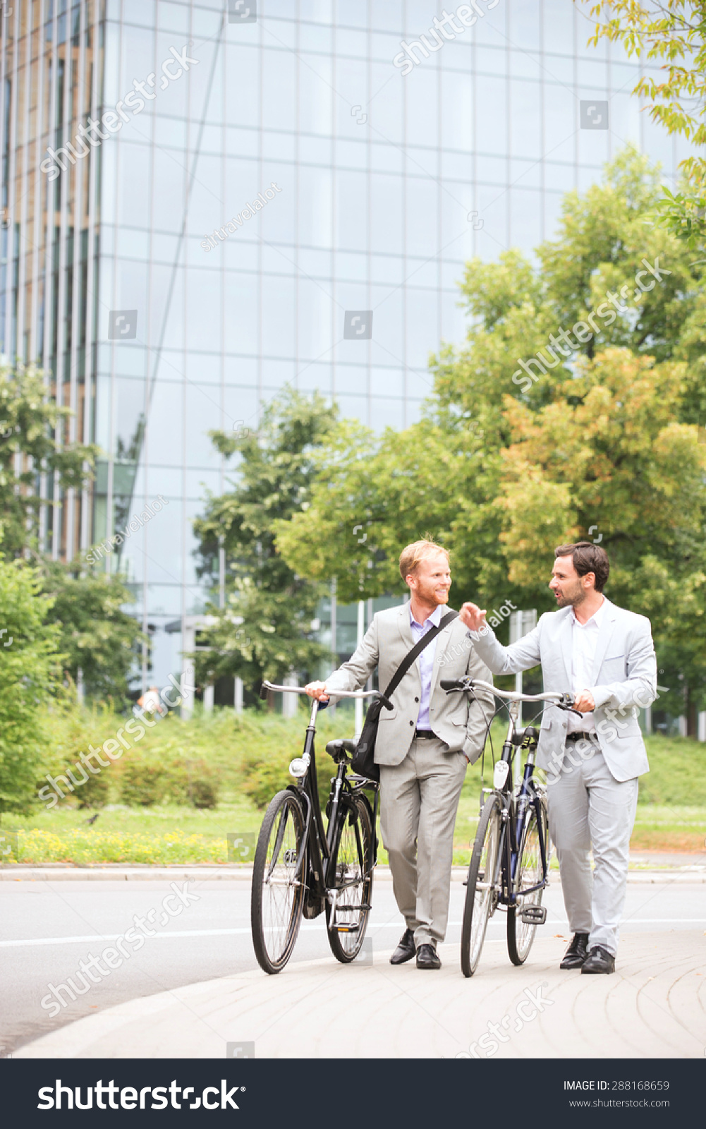 Businessmen talking while walking with bicycles on street #288168659