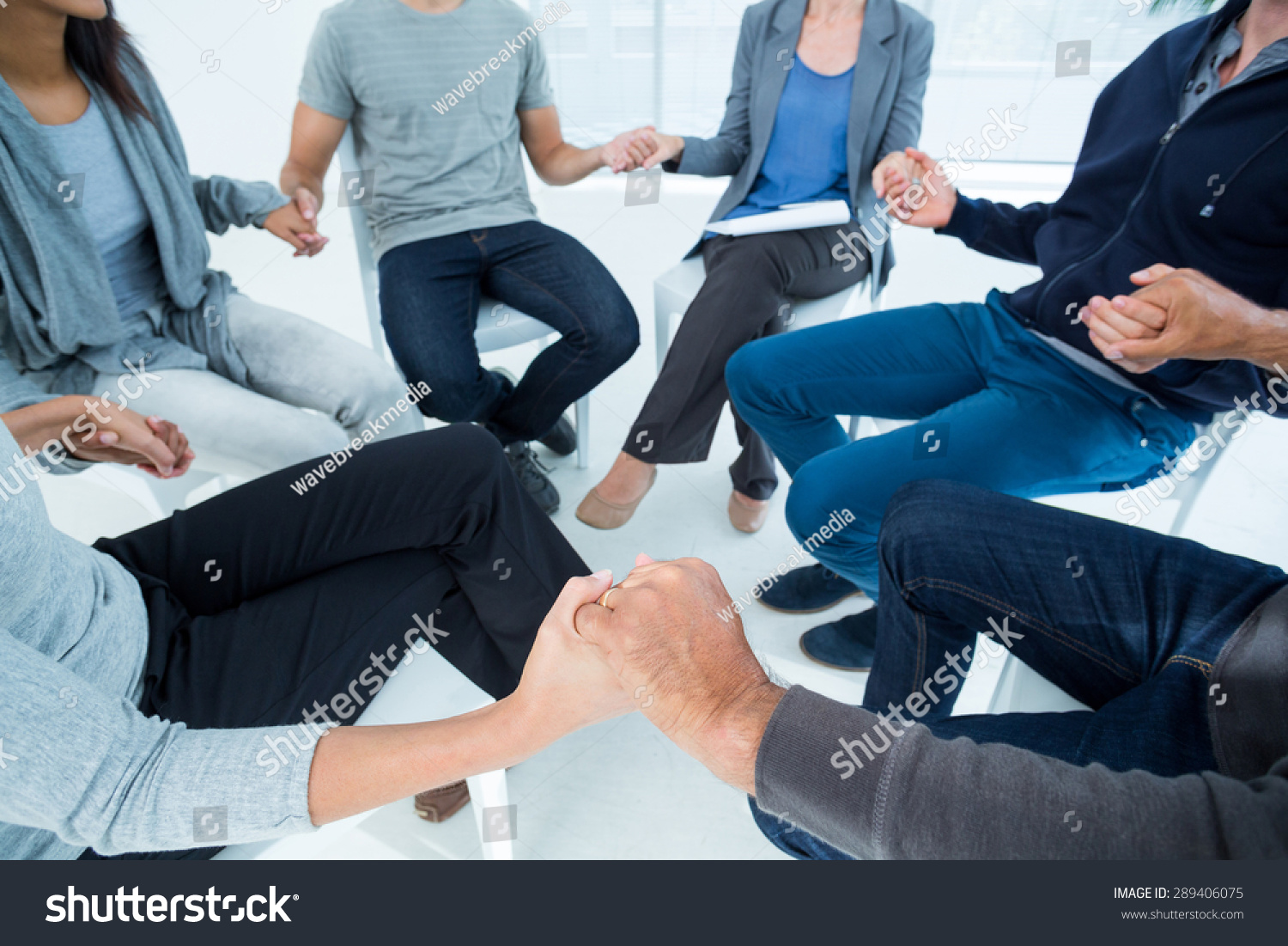 Group therapy in session sitting in a circle in a bright room #289406075