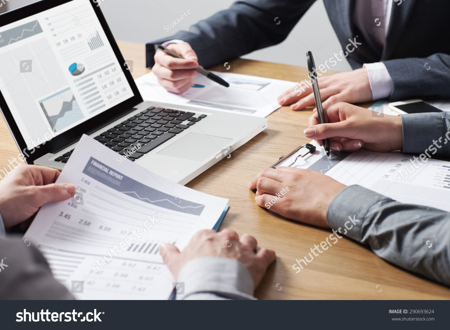 Business professionals working together at office desk, hands close up pointing out financial data on a report, teamwork concept #290693624