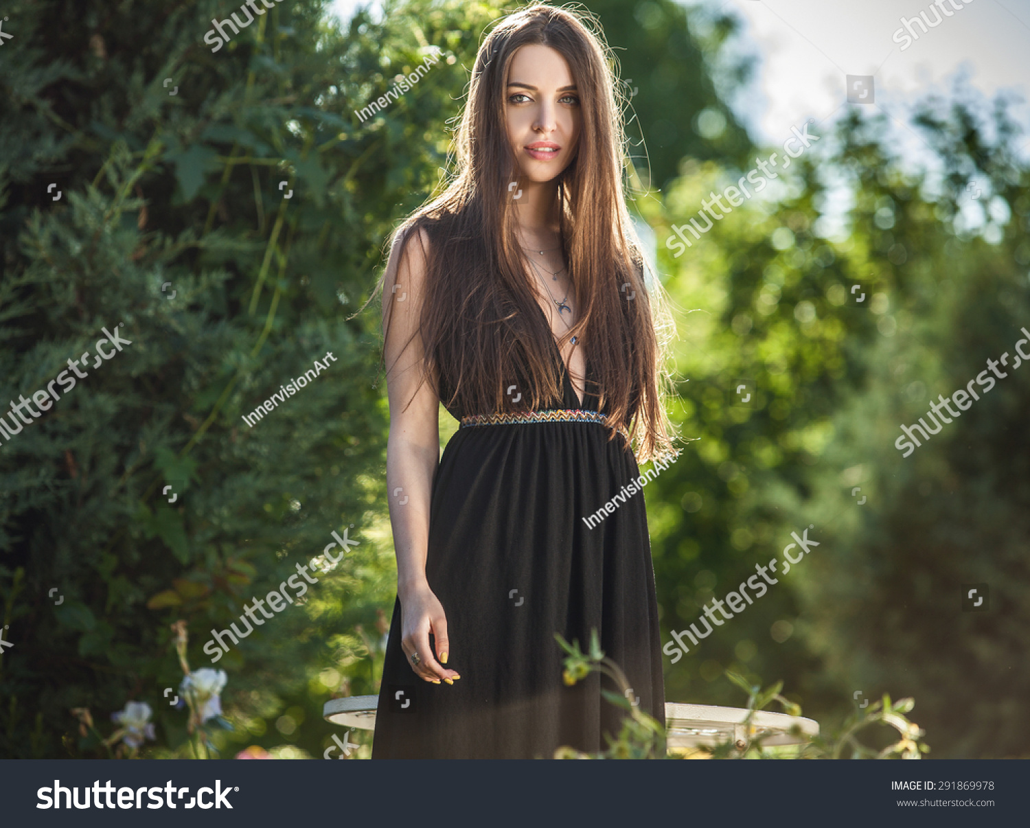 Outdoors portrait of beautiful young woman in luxury black dress posing in summer garden.
 #291869978