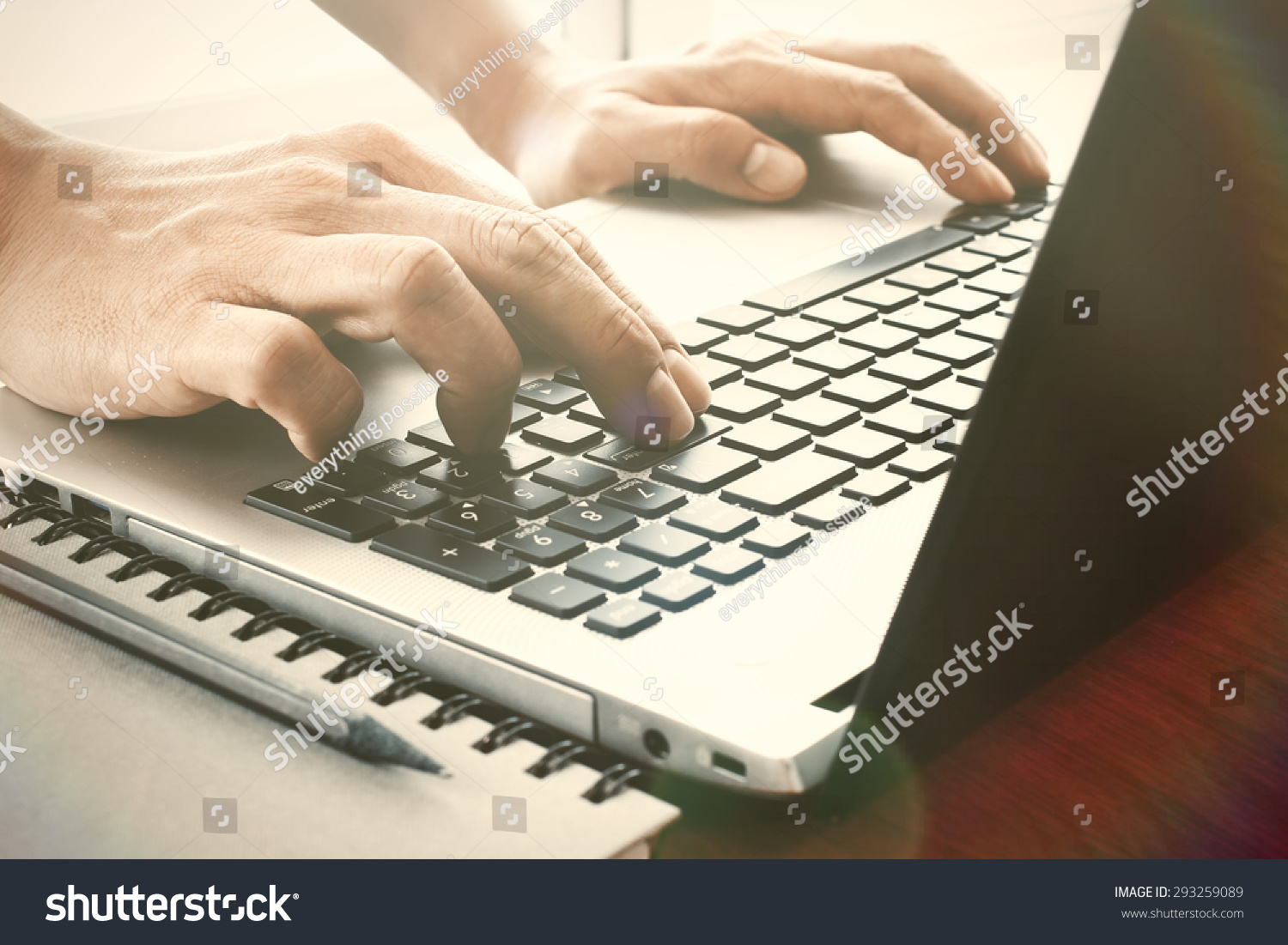 designer hand working with digital tablet and laptop and notebook stack and eye glass on wooden desk in office #293259089