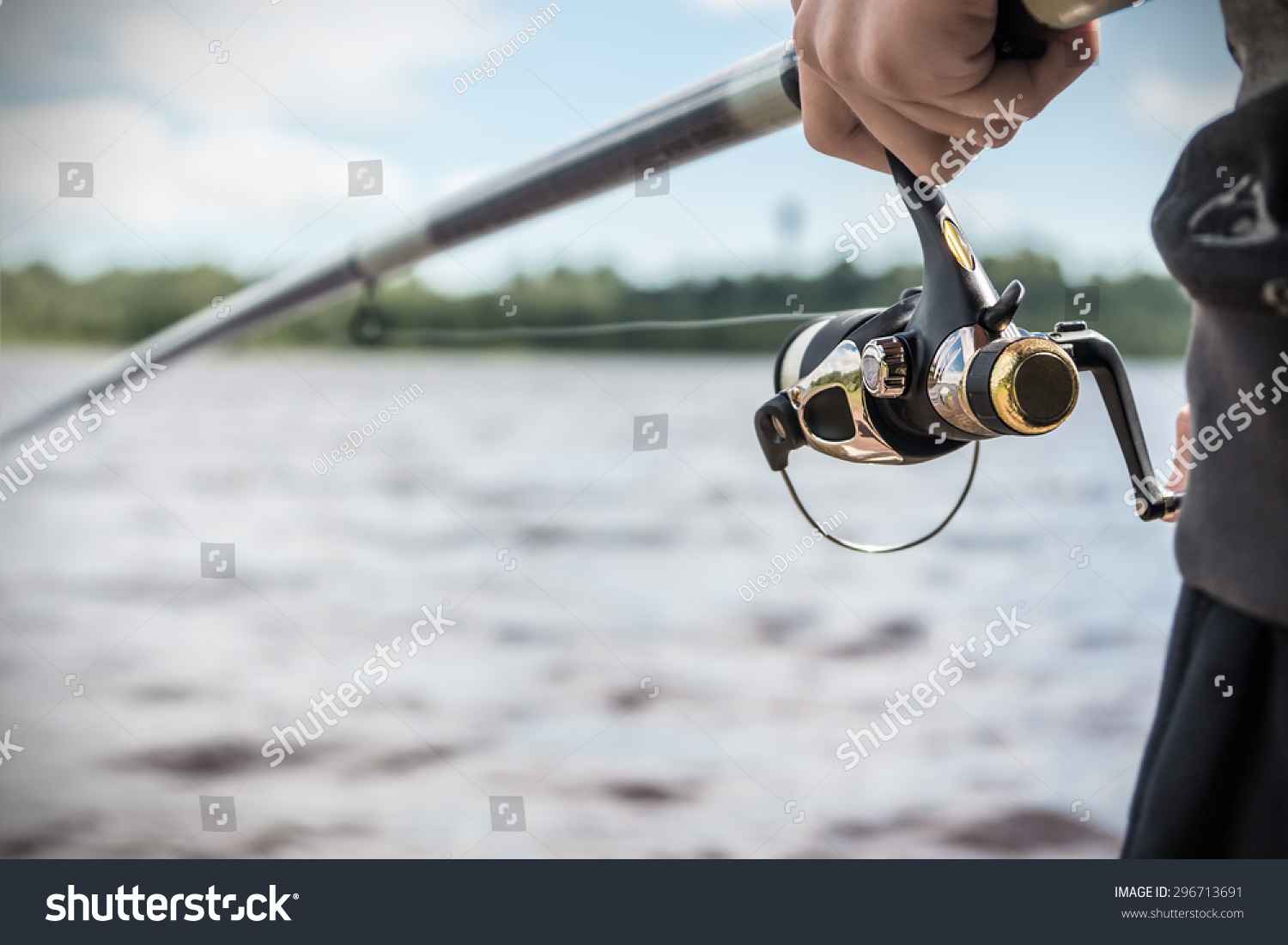 hand holding a fishing rod with reel. Focus on Fishing Reels  #296713691