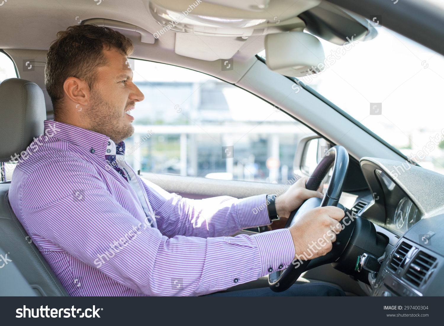 Young well-dressed man is driving his car with passion. He is looking forward with aggression #297400304