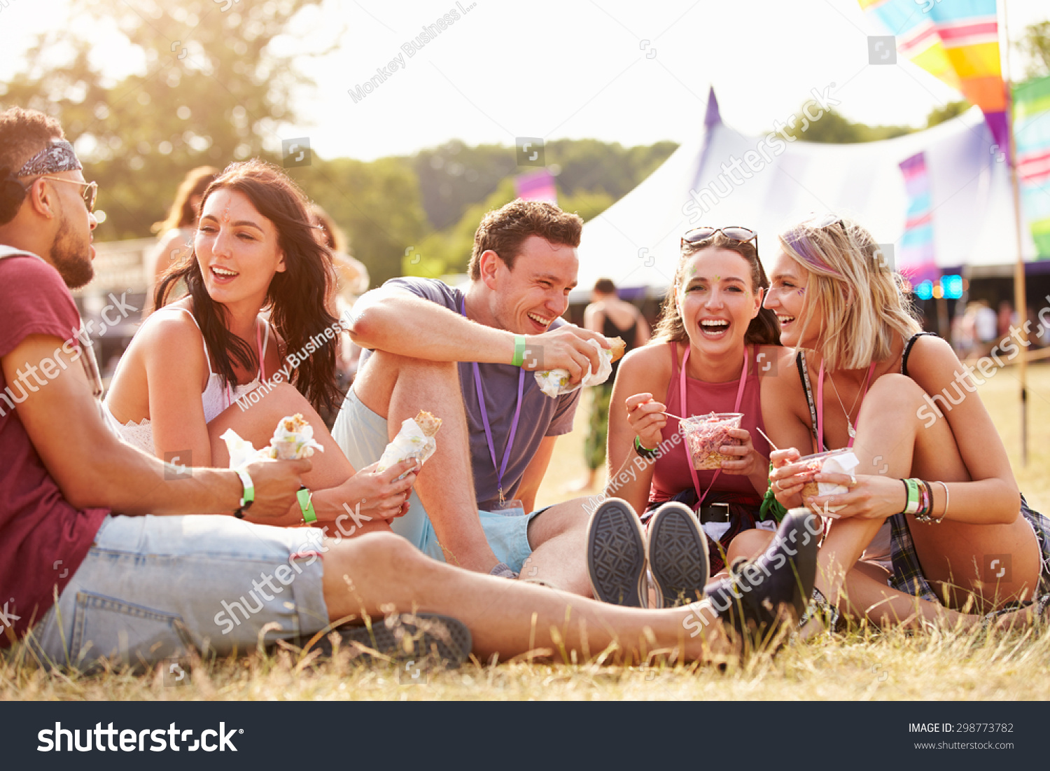 Friends sitting on the grass eating at a music festival #298773782