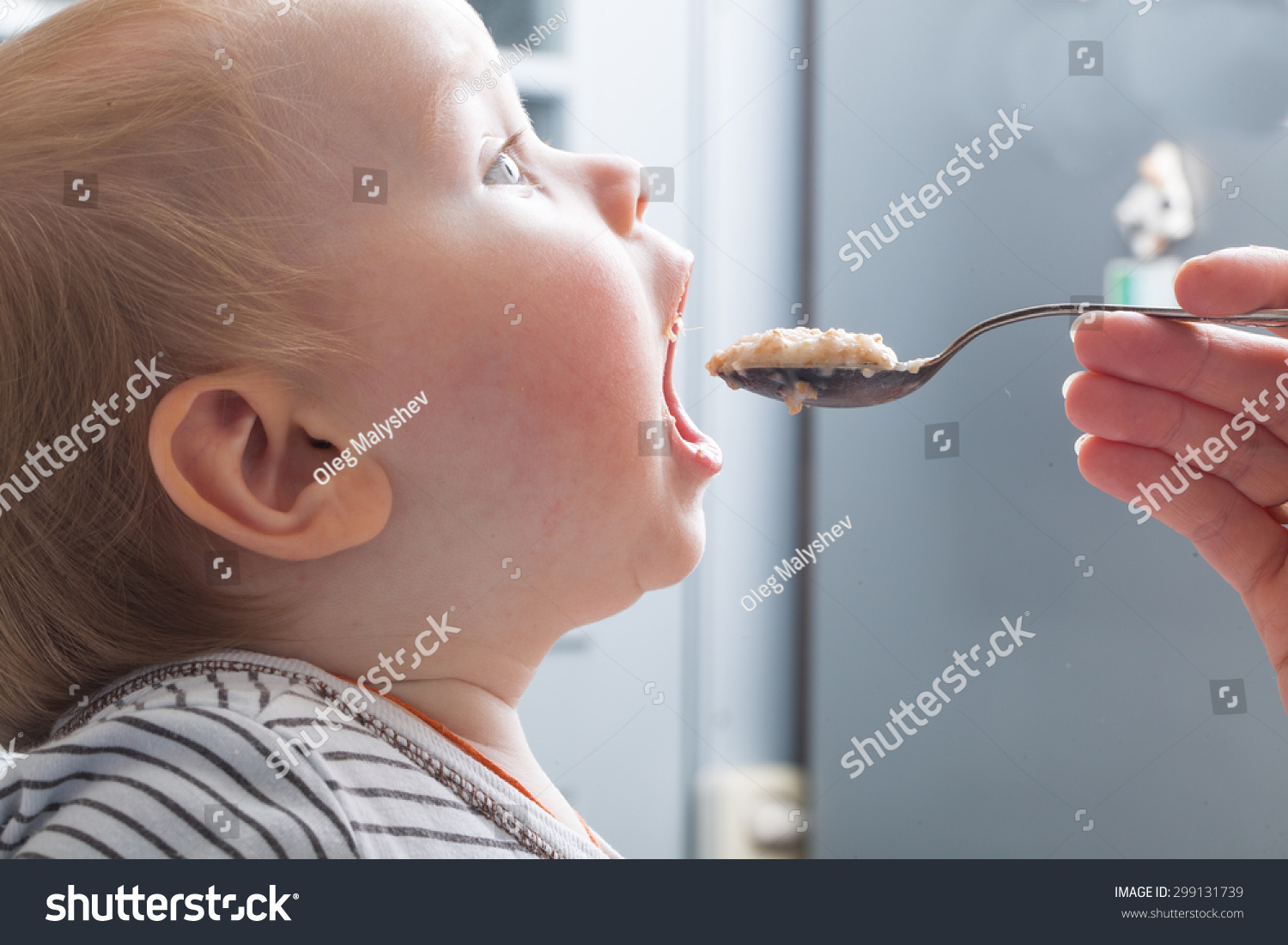 Mother feeds baby boy with a spoon porridge #299131739