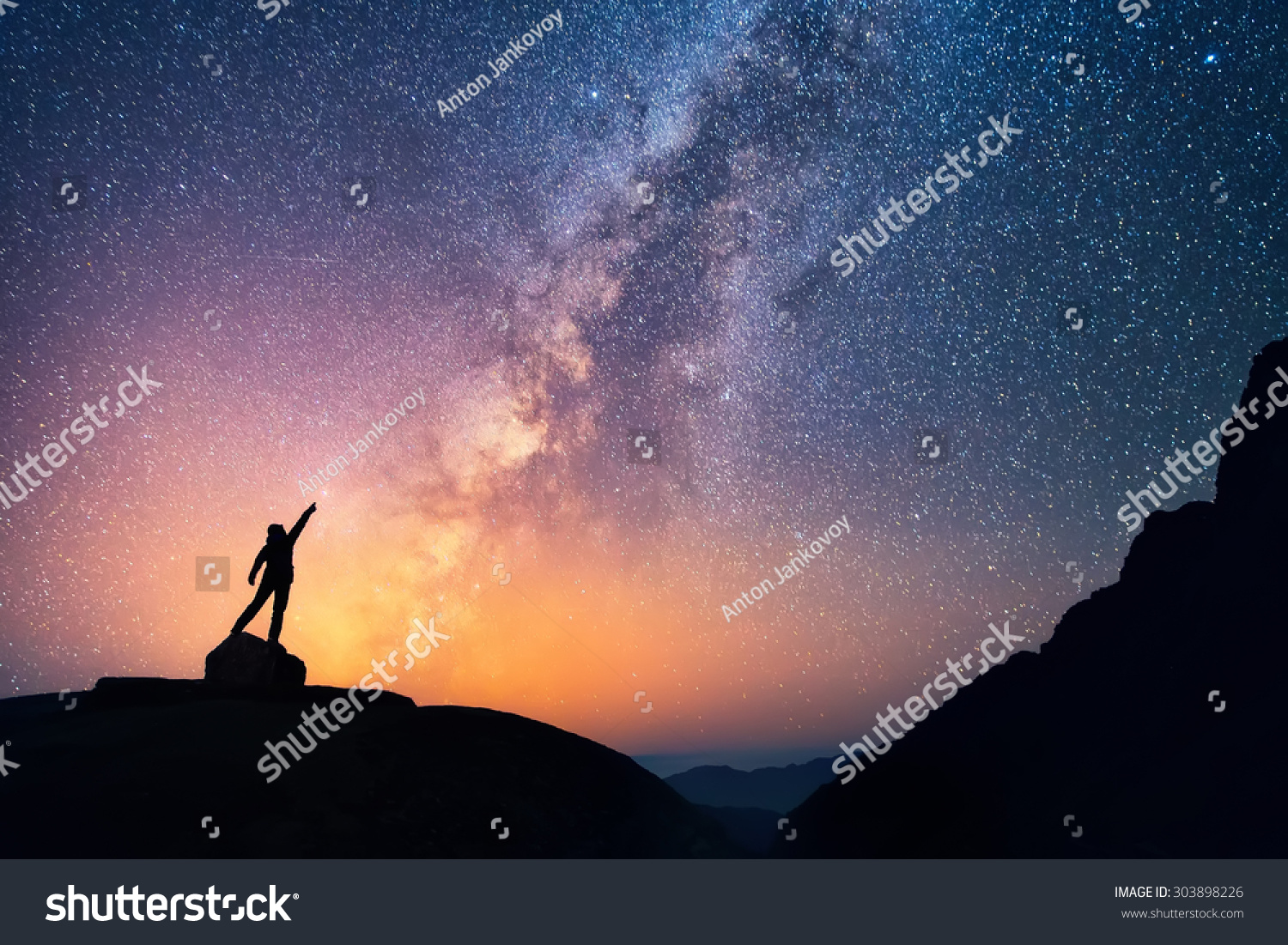 Star-catcher. A person is standing next to the Milky Way galaxy pointing on a bright star. #303898226