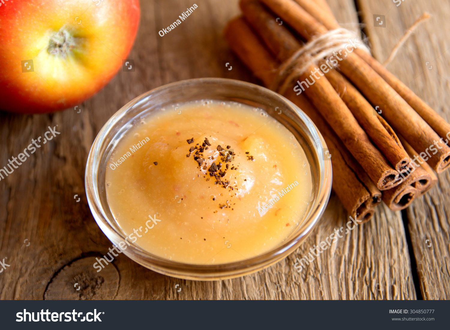 Fresh homemade applesauce (apple puree, mousse, baby food, sauce) with cinnamon (spices), spoon and apples on wooden table close up, horizontal #304850777