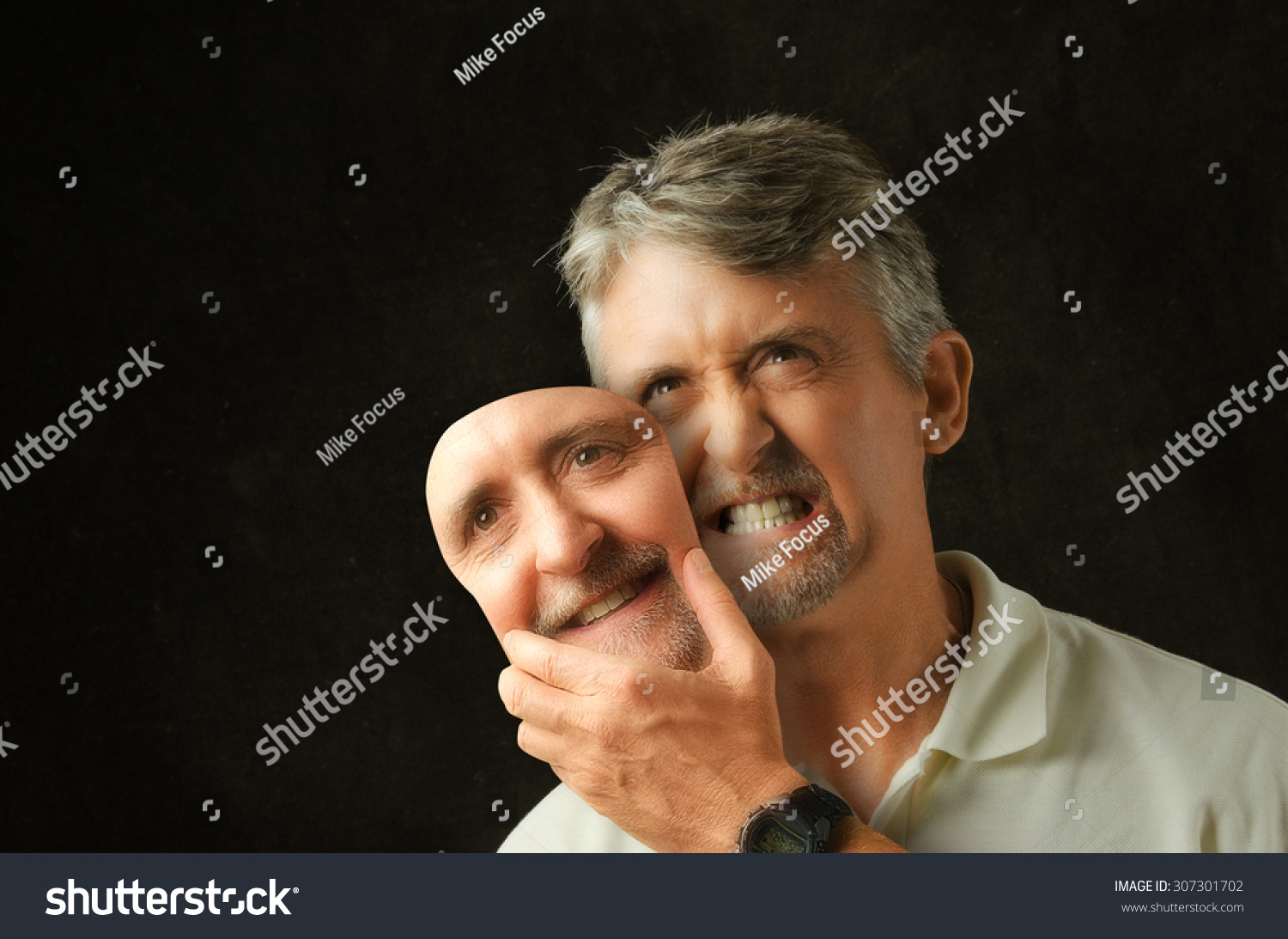 An angry, emotional, depressed, bipolar disorder man is revealing his true self as he takes off a fake smile happiness mask that looks exactly like his face.  #307301702