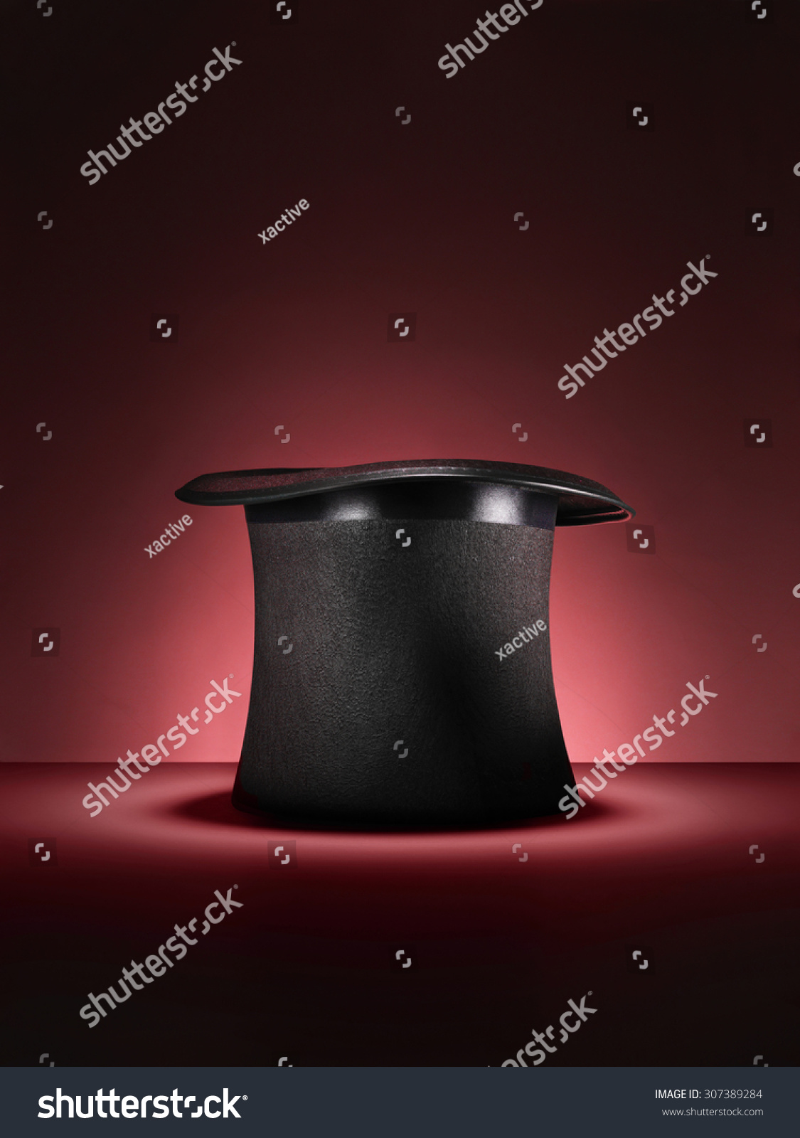 Shot of a traditional magicians style top hat set up for a trick or illusion on a red background with space left for the designer to add an object or type.  #307389284