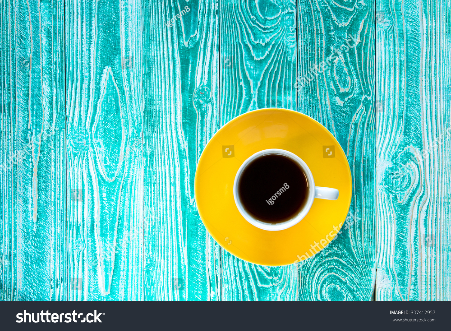 cup of black tea on yellow plate on turquoise colored old wooden table  top view #307412957