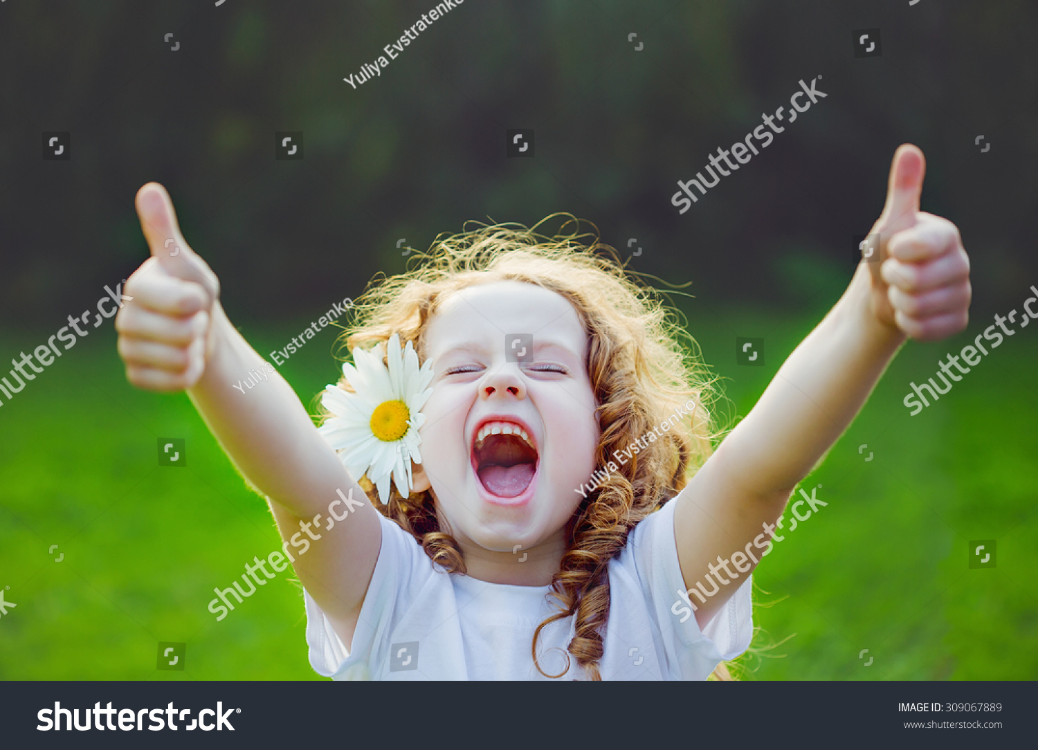 Laughing girl with daisy in her hairs, showing thumbs up. #309067889