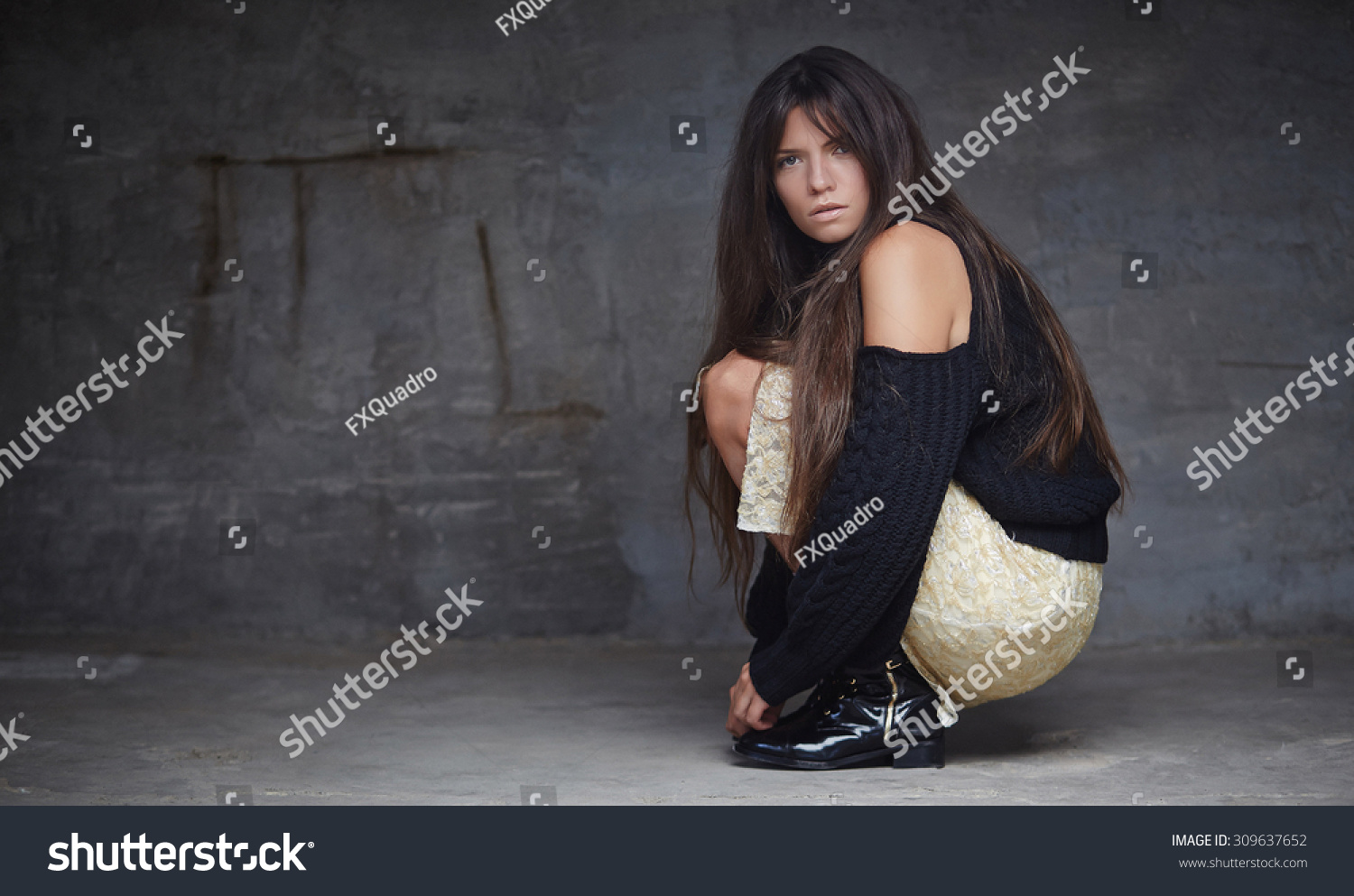 Full body portrait of brunette fashion woman who sitting on the floor over grey wall. #309637652
