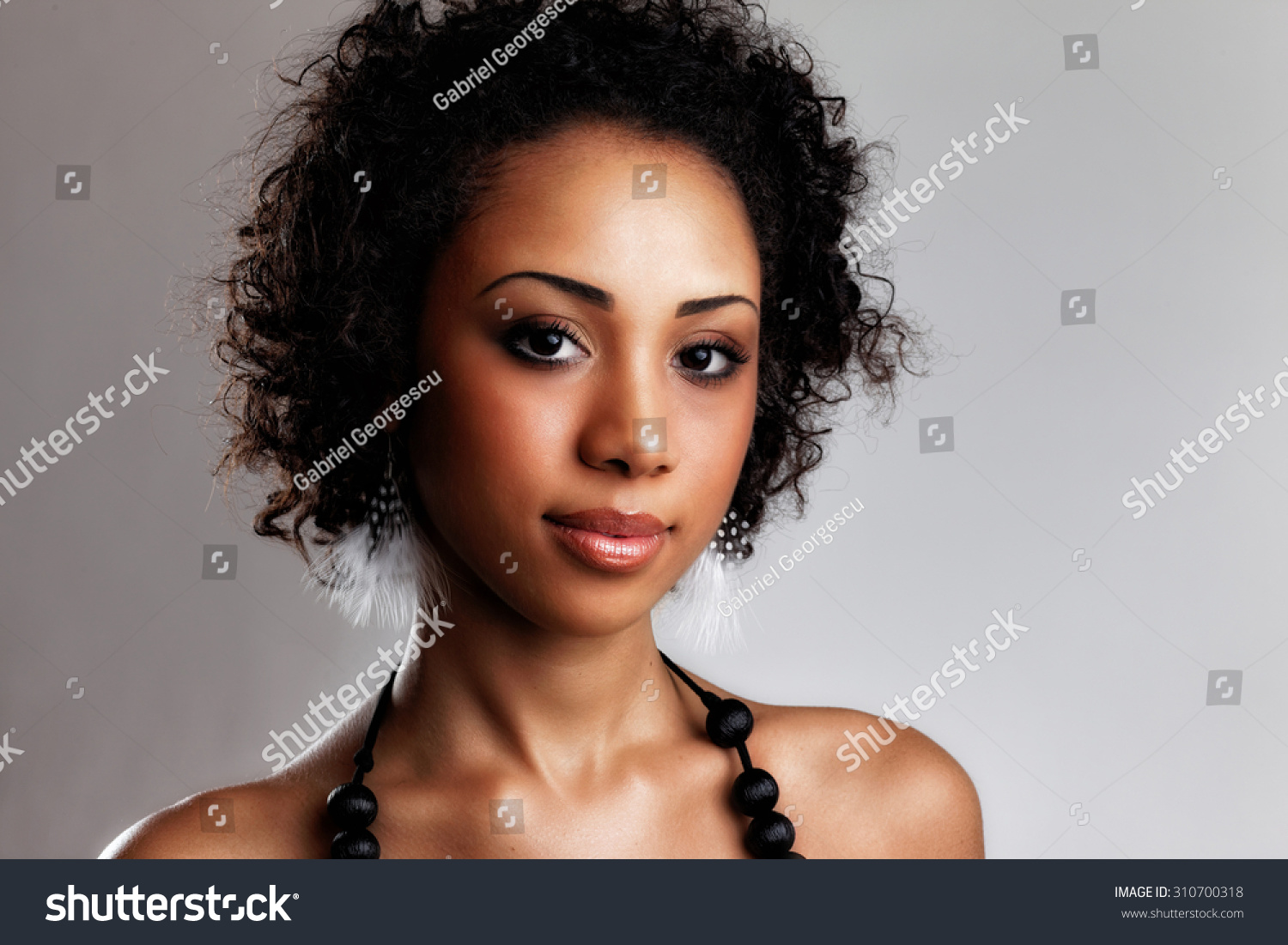 Beautiful black woman posing in a studio. Perfect makeup. Beauty fashion .Close-up portrait of attractive young model with bright make-up. #310700318