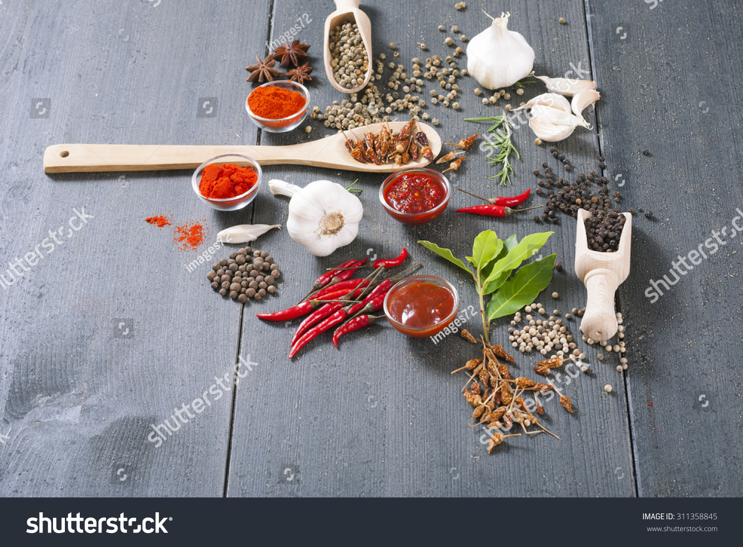 fresh and dried chili fruits, peppercorn, pepper powder, sauce and garlic, bay leaves on old black wooden table background #311358845