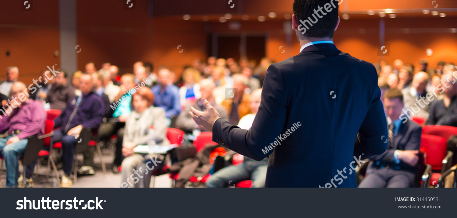 Speaker at Business Conference with Public Presentations. Audience at the conference hall. Entrepreneurship club. Rear view. Panoramic composition. Background blur. #314450531