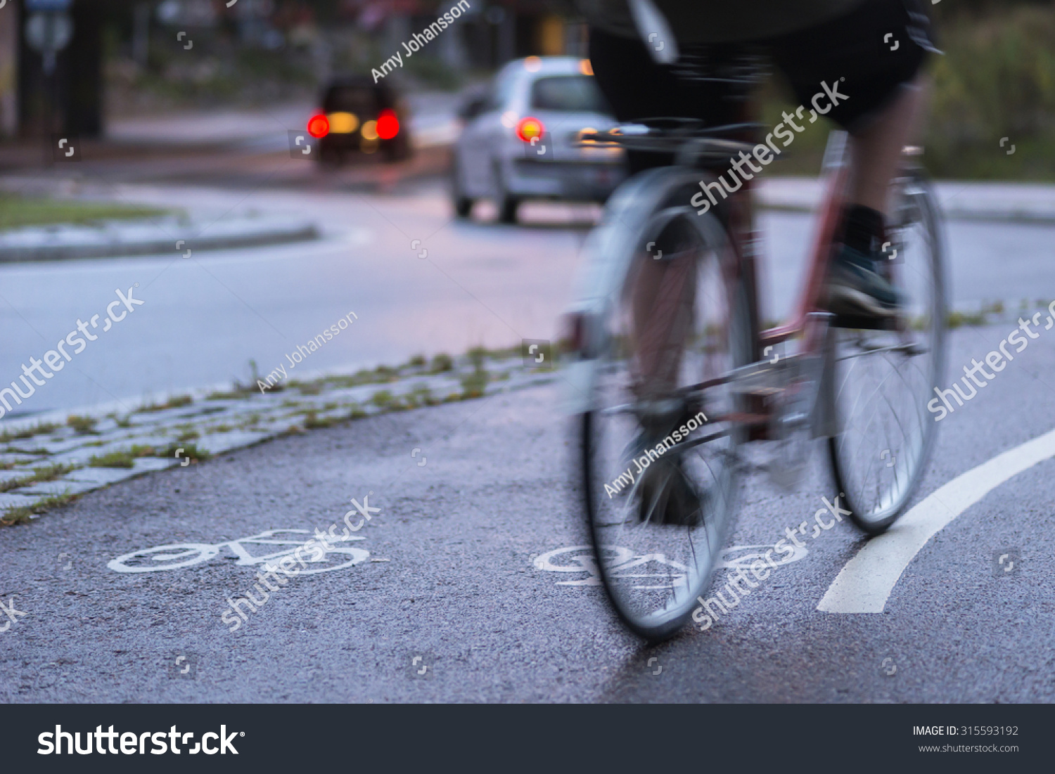 Cyclist in blurred motion on cycling path by busy street at night #315593192