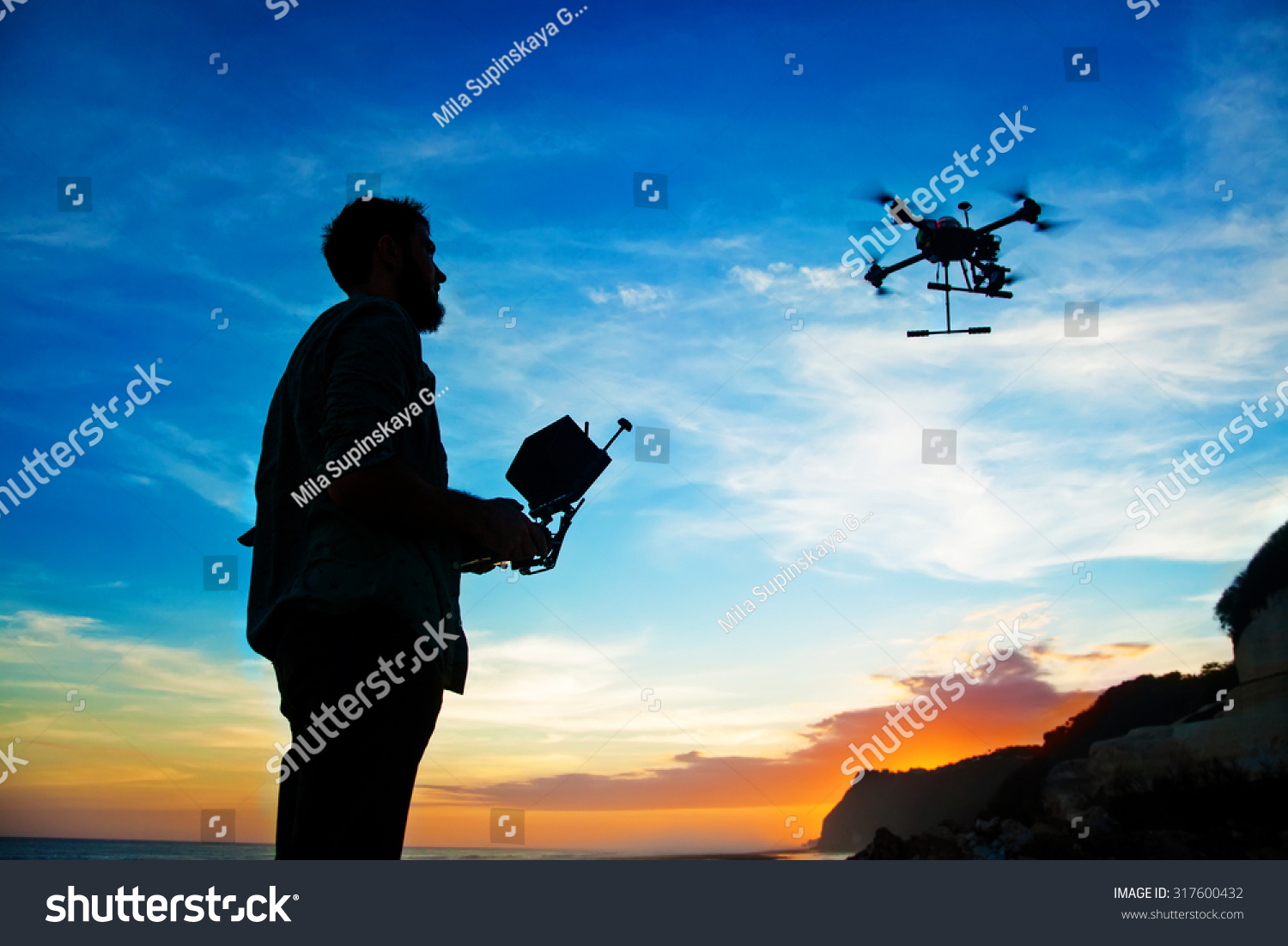 man playing with the drone. silhouette against the sunset sky #317600432