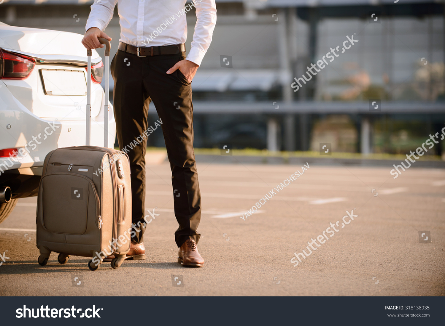 Ready for official journey. Pleasant confident businessman standing near his car and holding suitcase while going to travel #318138935