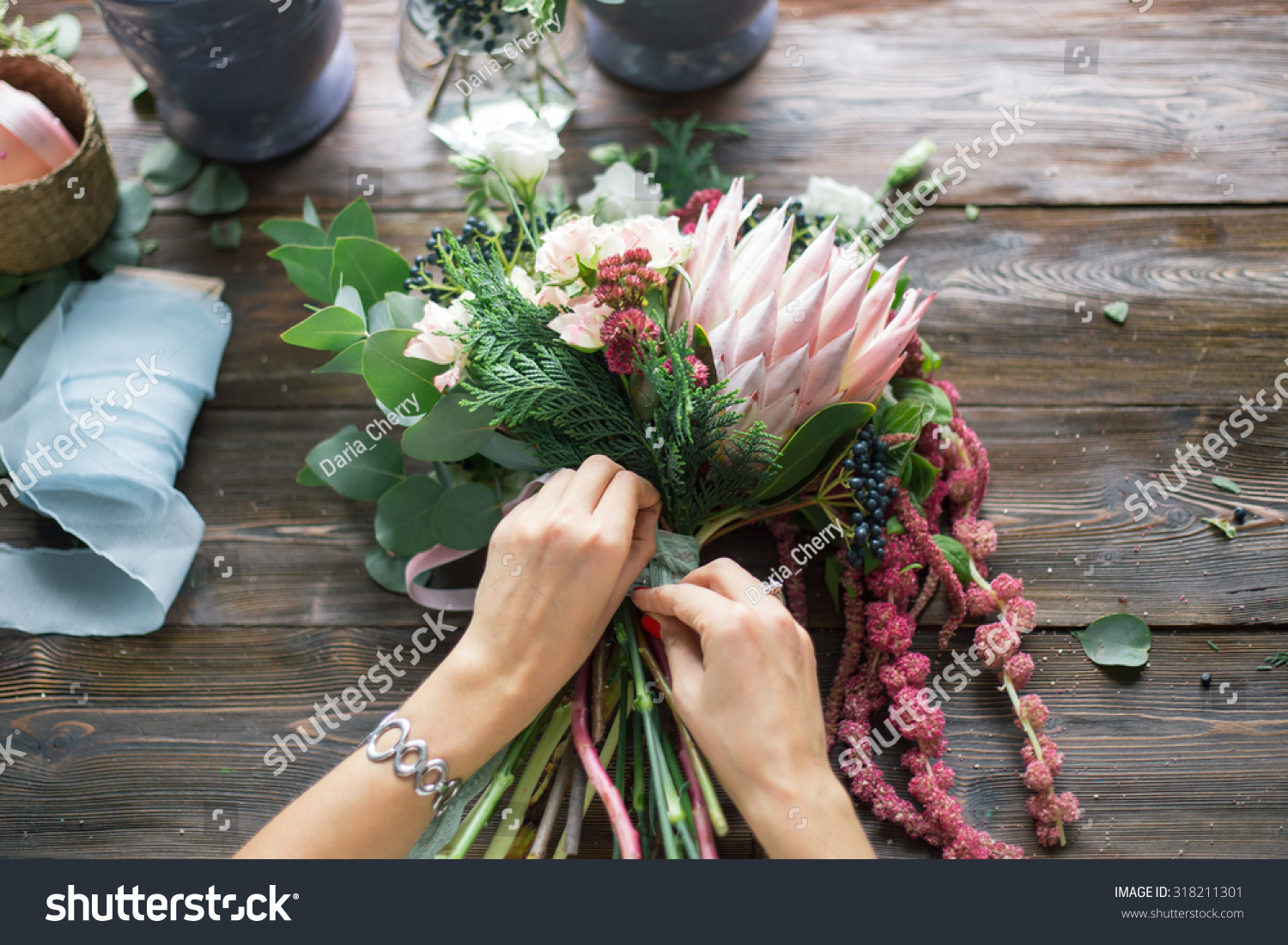 Florist at work: pretty young blond woman making fashion modern bouquet of different flowers #318211301