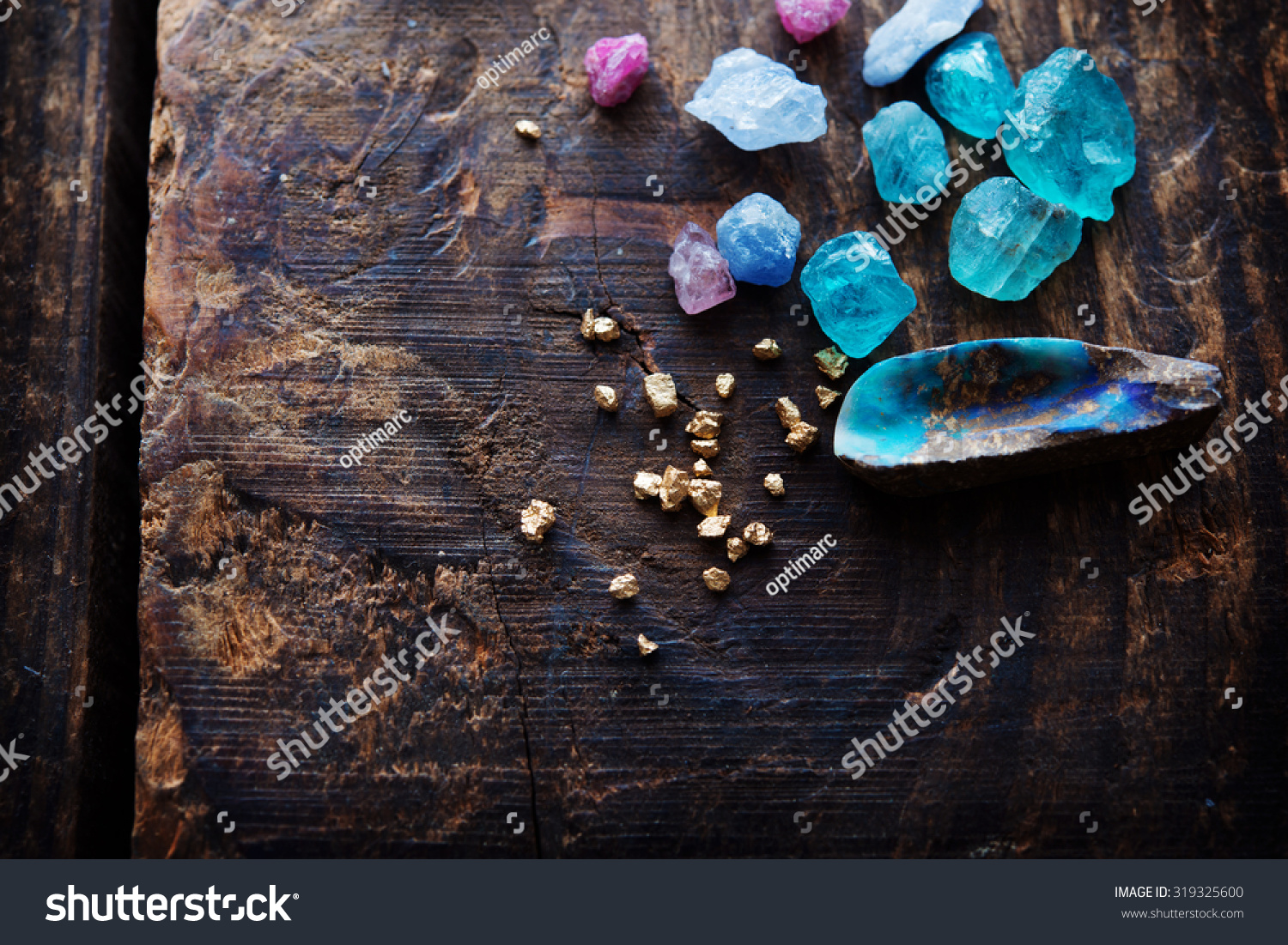 Treasure hunting. Mining for gems. Gold and gems on rough wooden surface. #319325600