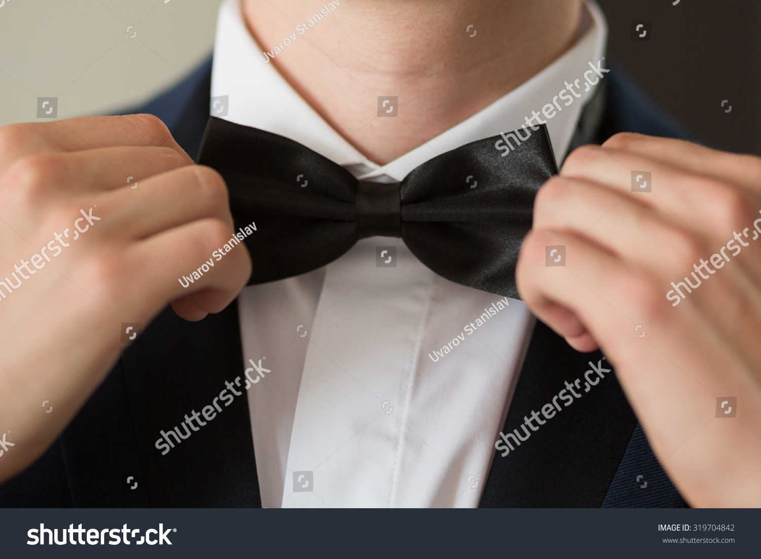Man's hands touches bow-tie on a suit #319704842