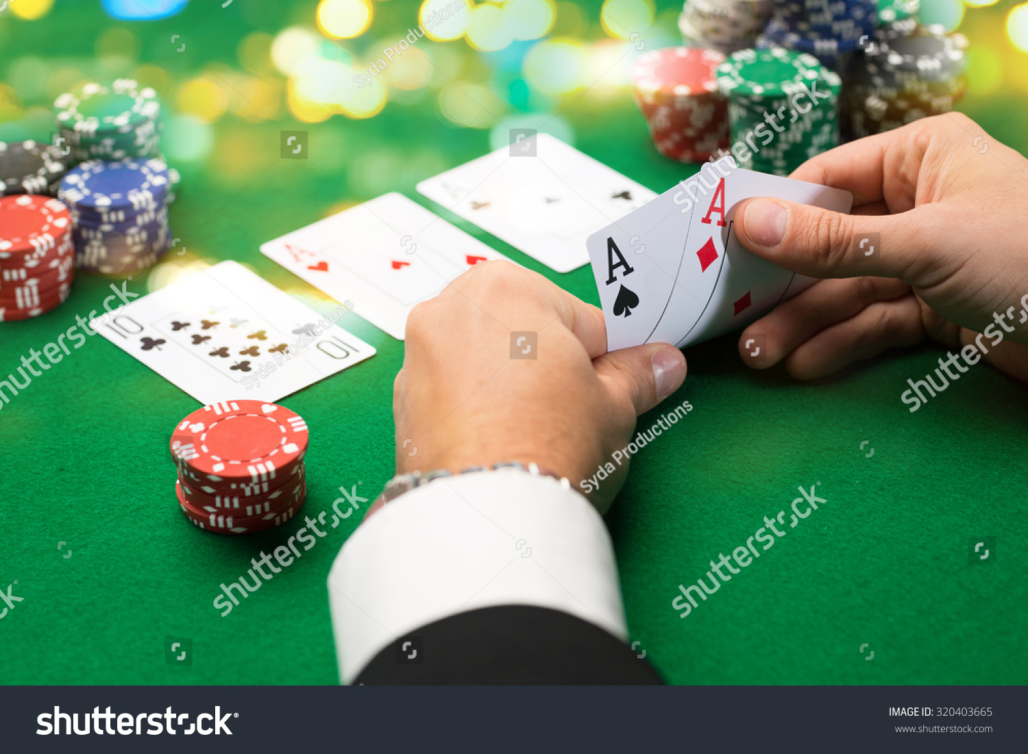 casino, gambling, poker, people and entertainment concept - close up of poker player with playing cards and chips at green casino table over holidays lights background #320403665