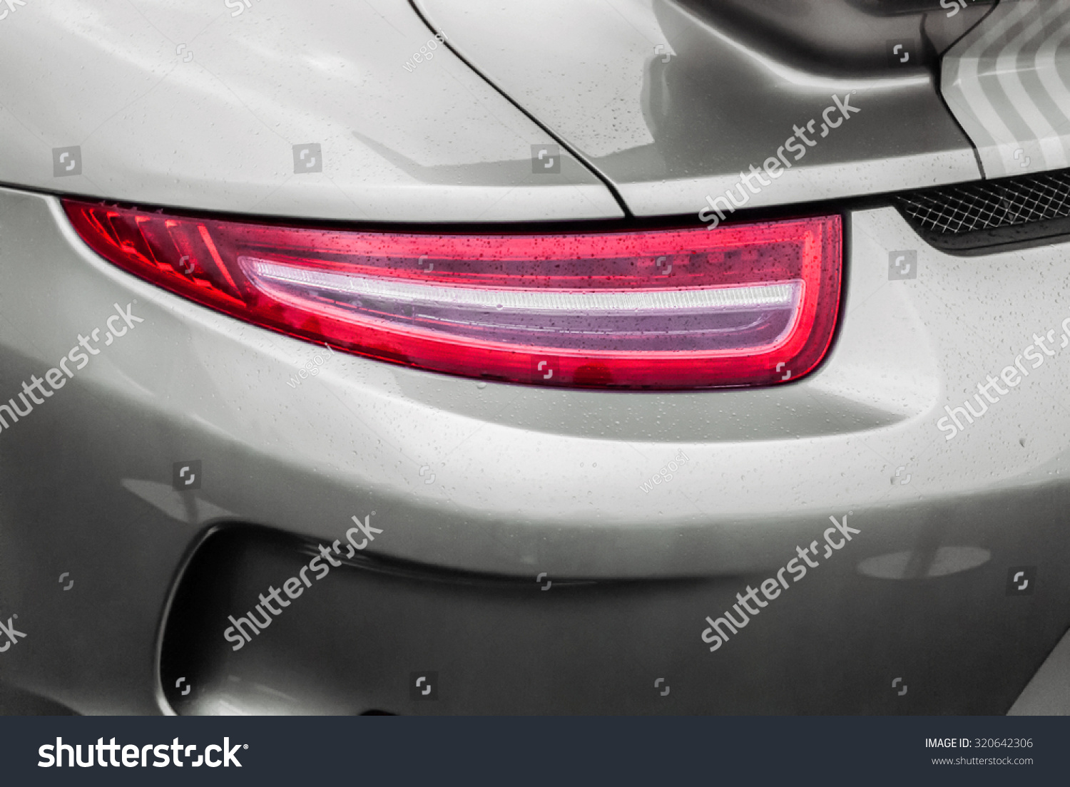 Tail light of sport grey car with rain drops and shadows. Closeup headlights of car. Modern luxury car close-up banner background. Concept of expensive, sports auto Closeup headlights Porsche 911 #320642306