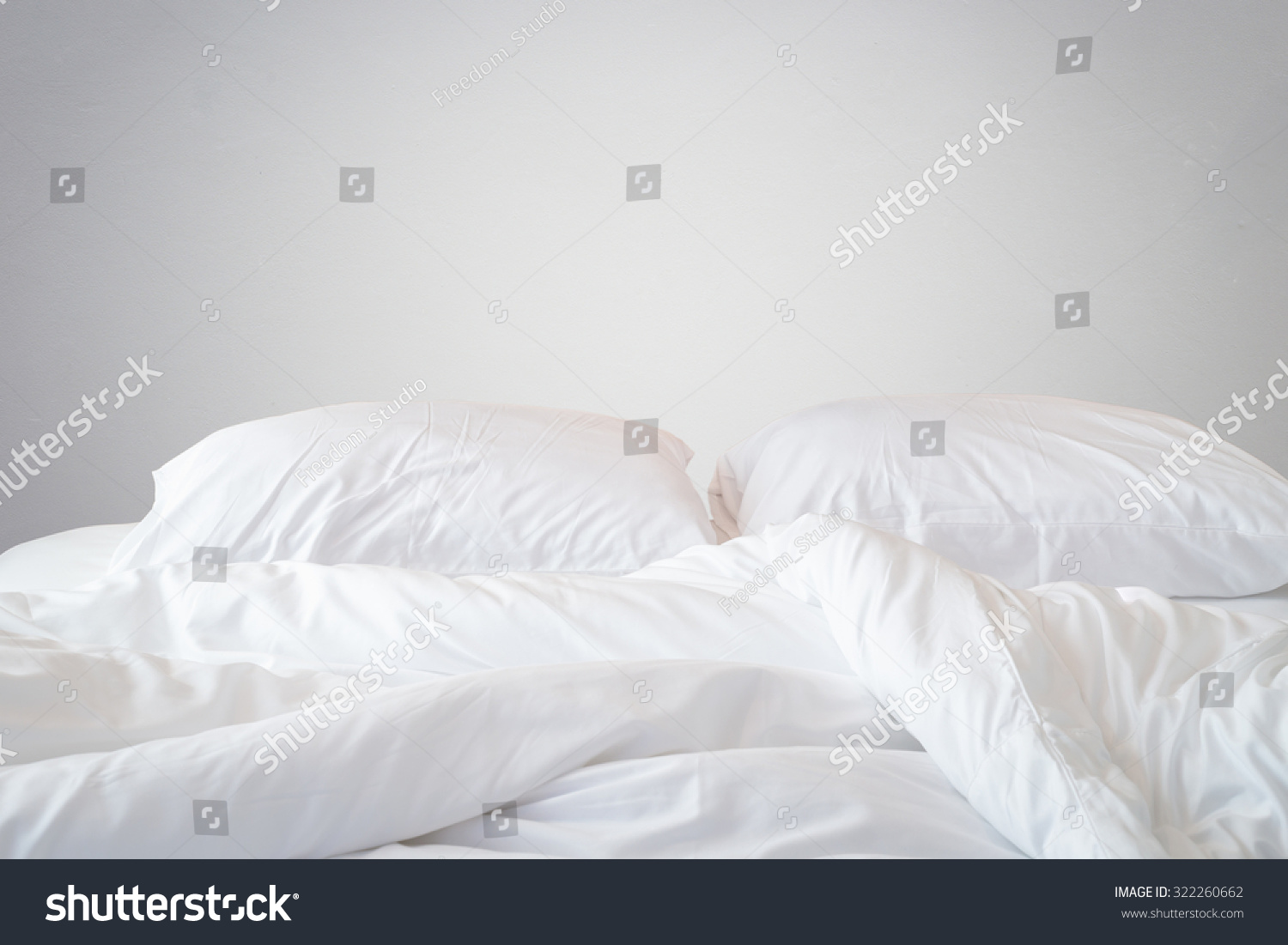 Close up white bedding sheets and pillow on natural stone wall room background, Messy bed concept #322260662